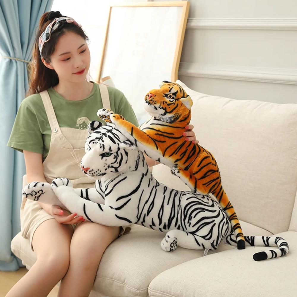 Woman sitting on a couch with plush toys depicting a tiger and a black and white striped cat.