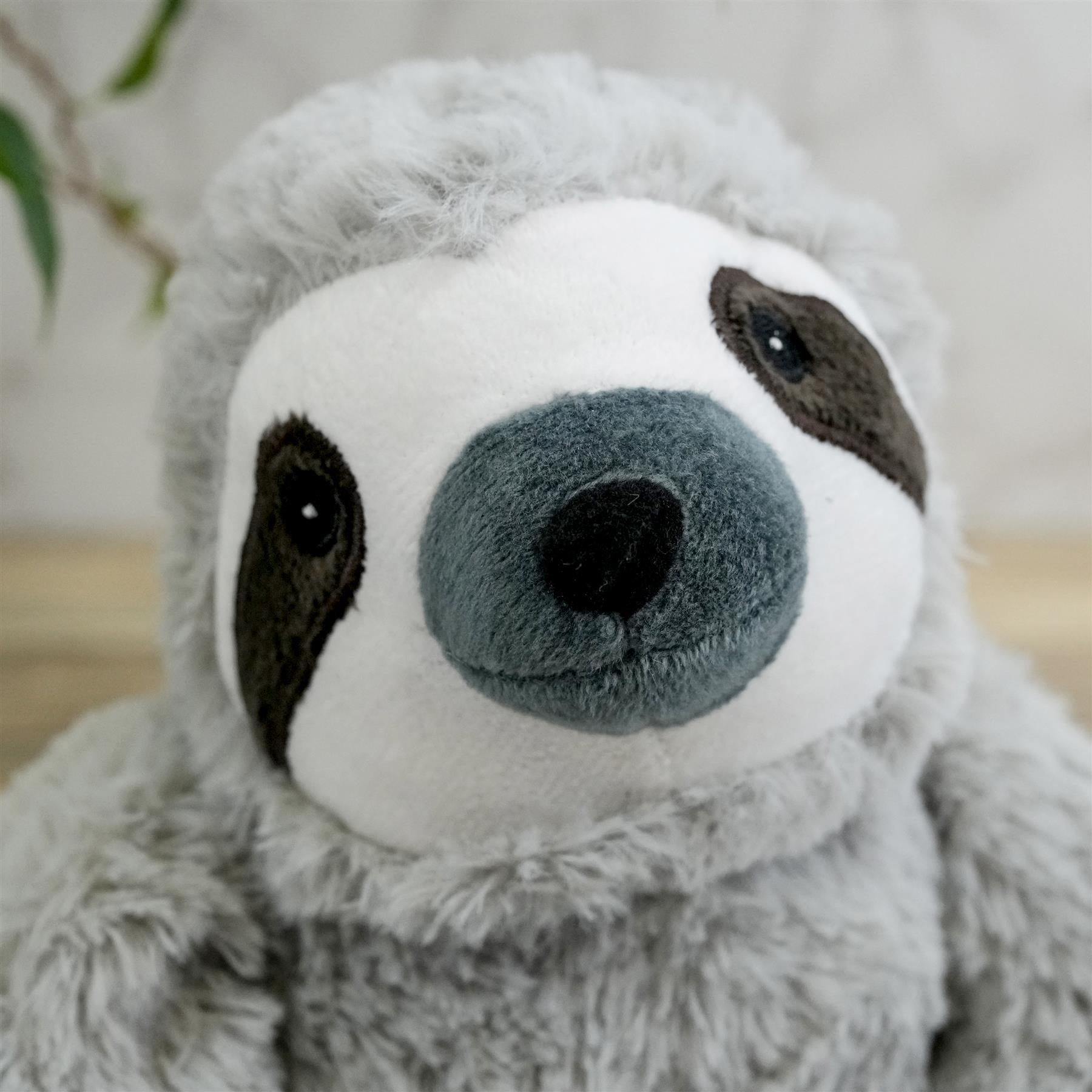A soft, cuddly sloth plush toy with a white and grey fur, black eyes, and a grey nose. It has a long, grey-tinged fur tail and arms, making it look like it's ready to embrace you. - The Magic Toy Shop