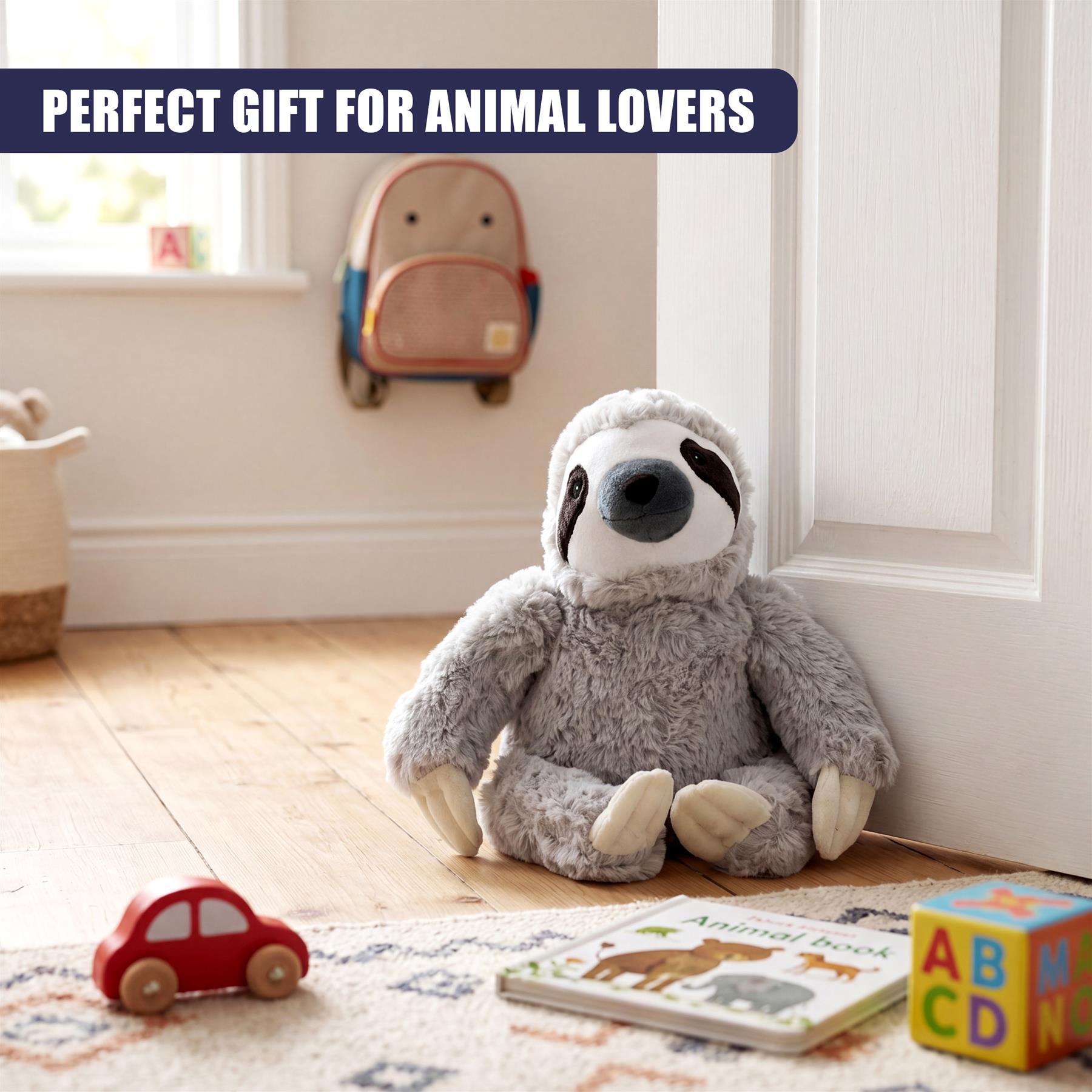 Plush gray sloth door stopper near a red toy car, children's book, and white door.