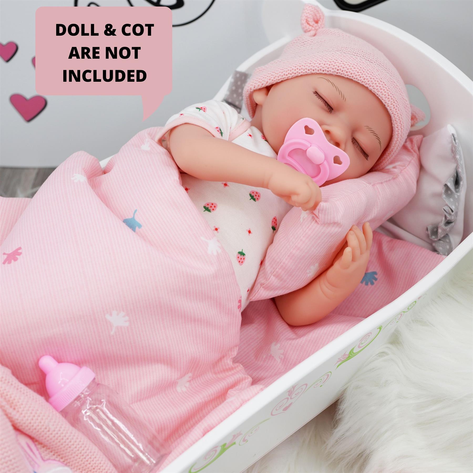 A pink baby doll in a crib, lying down under a blanket with pacifier. - The Magic Toy Shop