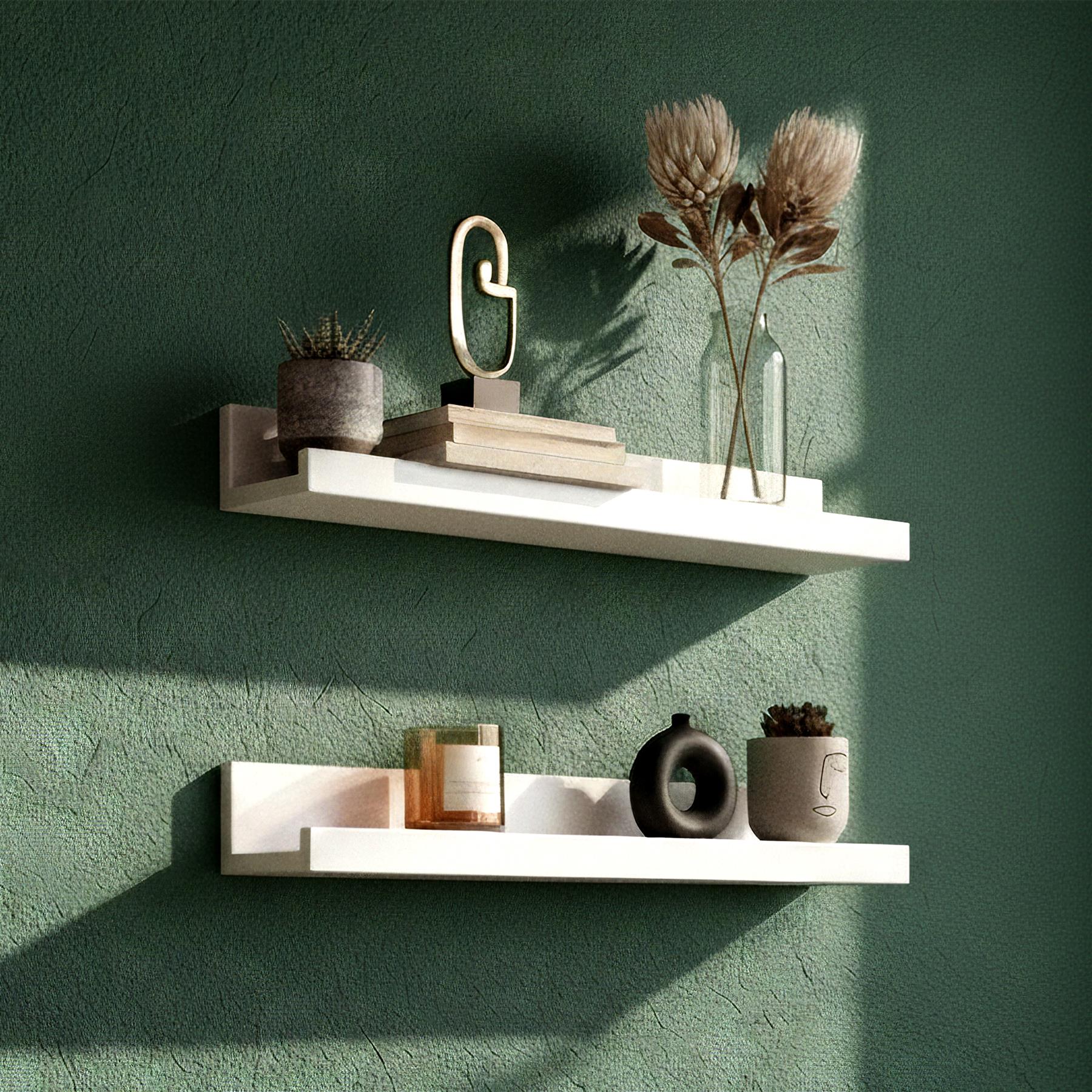 A modern shelf with two white shelves, one above the other, on a green wall. Each shelf has a few decorative items, including a small plant, a book, and a vase with dried flowers. - The Magic Toy Shop