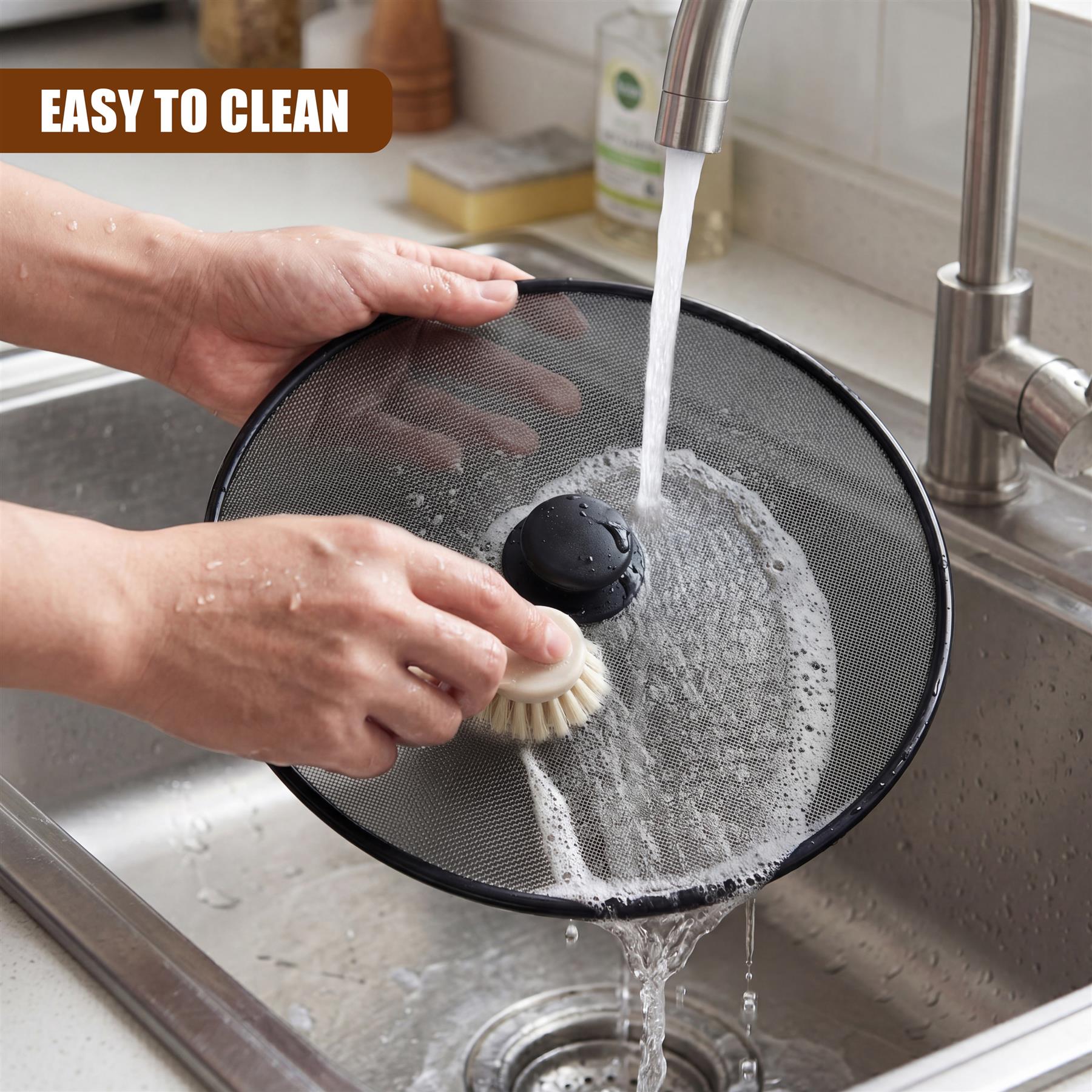 Hands clean a black mesh splatter screen under running water in a kitchen sink.