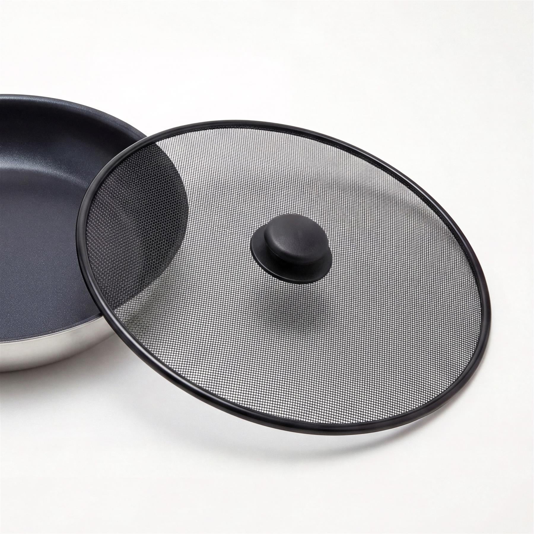 Round black perforated metal splatter screen with a central handle, displayed next to a dark cooking pan.
