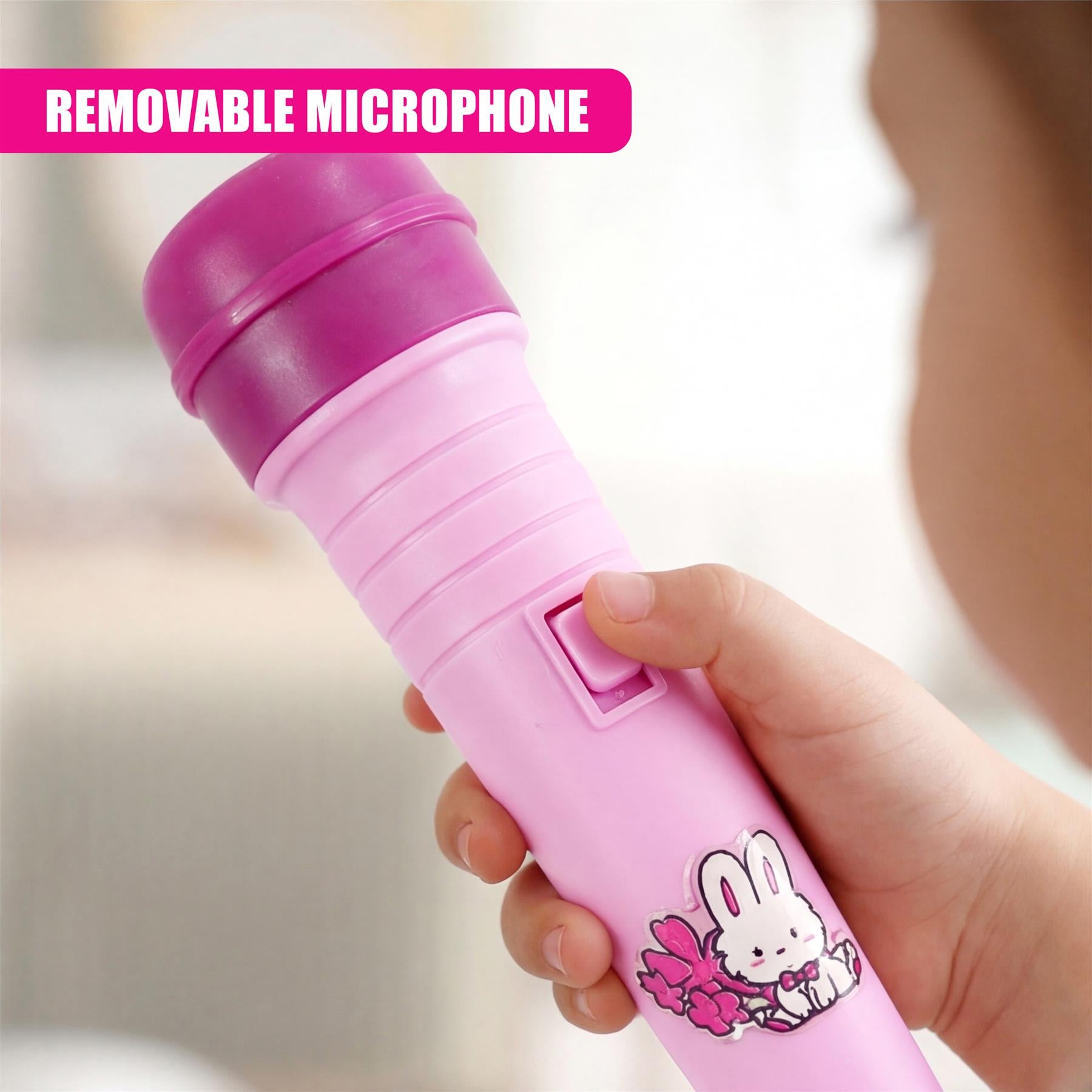 A pink toy microphone decorated with a white bunny illustration is held by a child's hand.