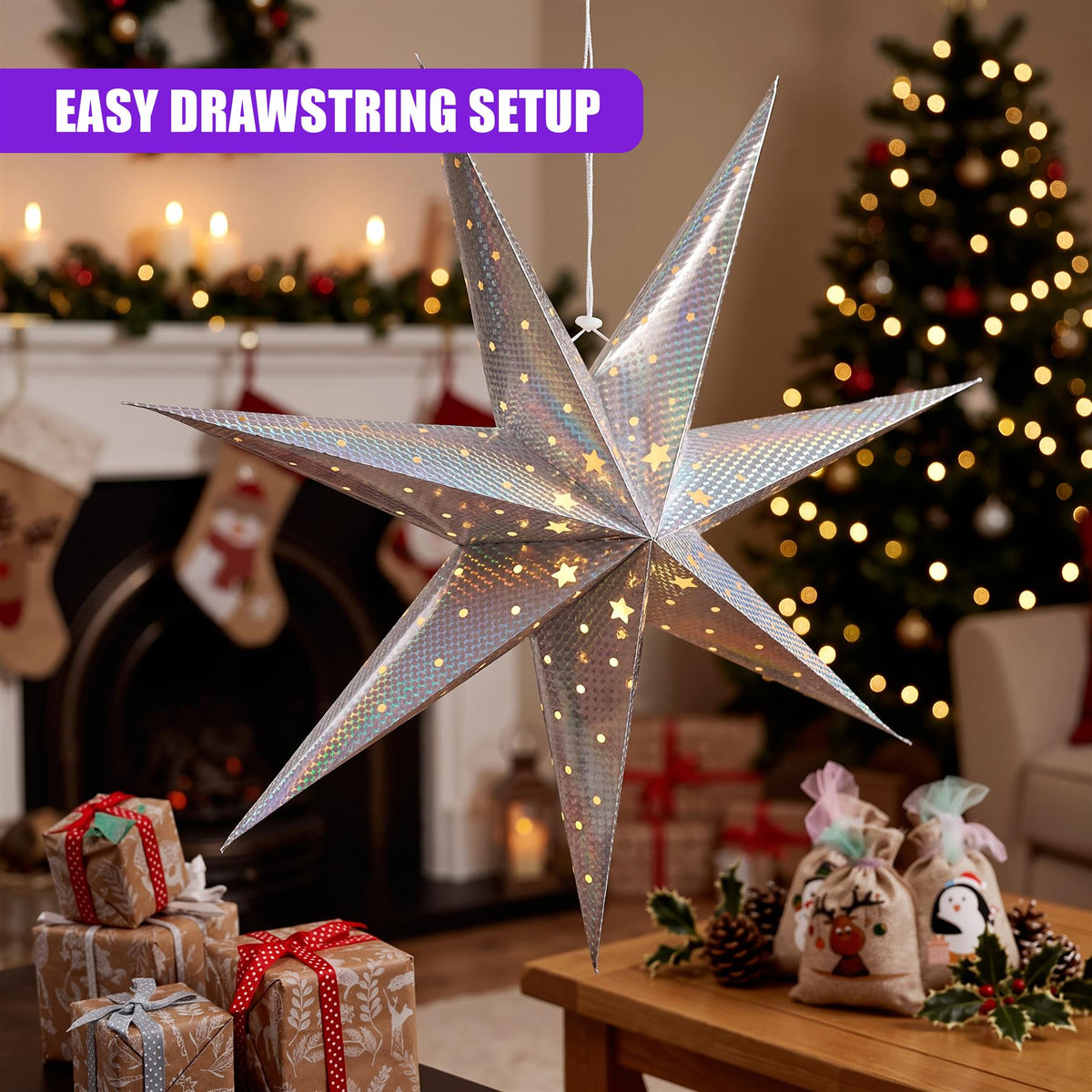A silver LED paper star lantern hangs in a festive room setting, featuring an easy drawstring setup