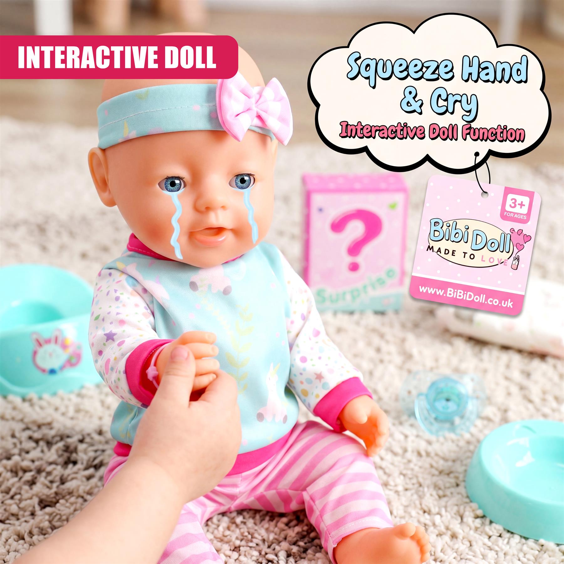 A baby doll with visible tears sits in a hand near light blue, plastic accessories and bowls.