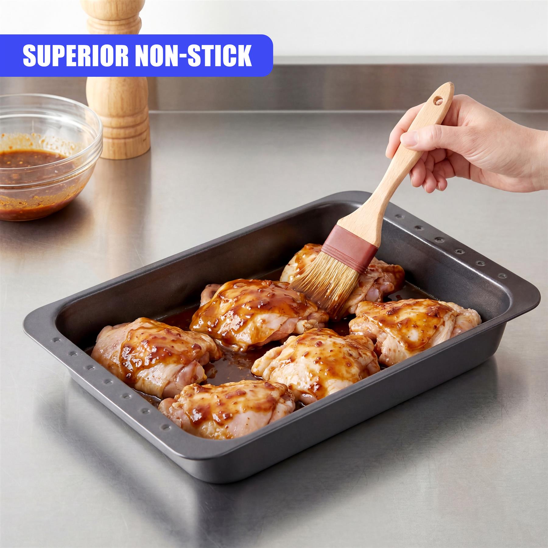 Roasted poultry in a baking pan receives a glaze from a basting brush.
