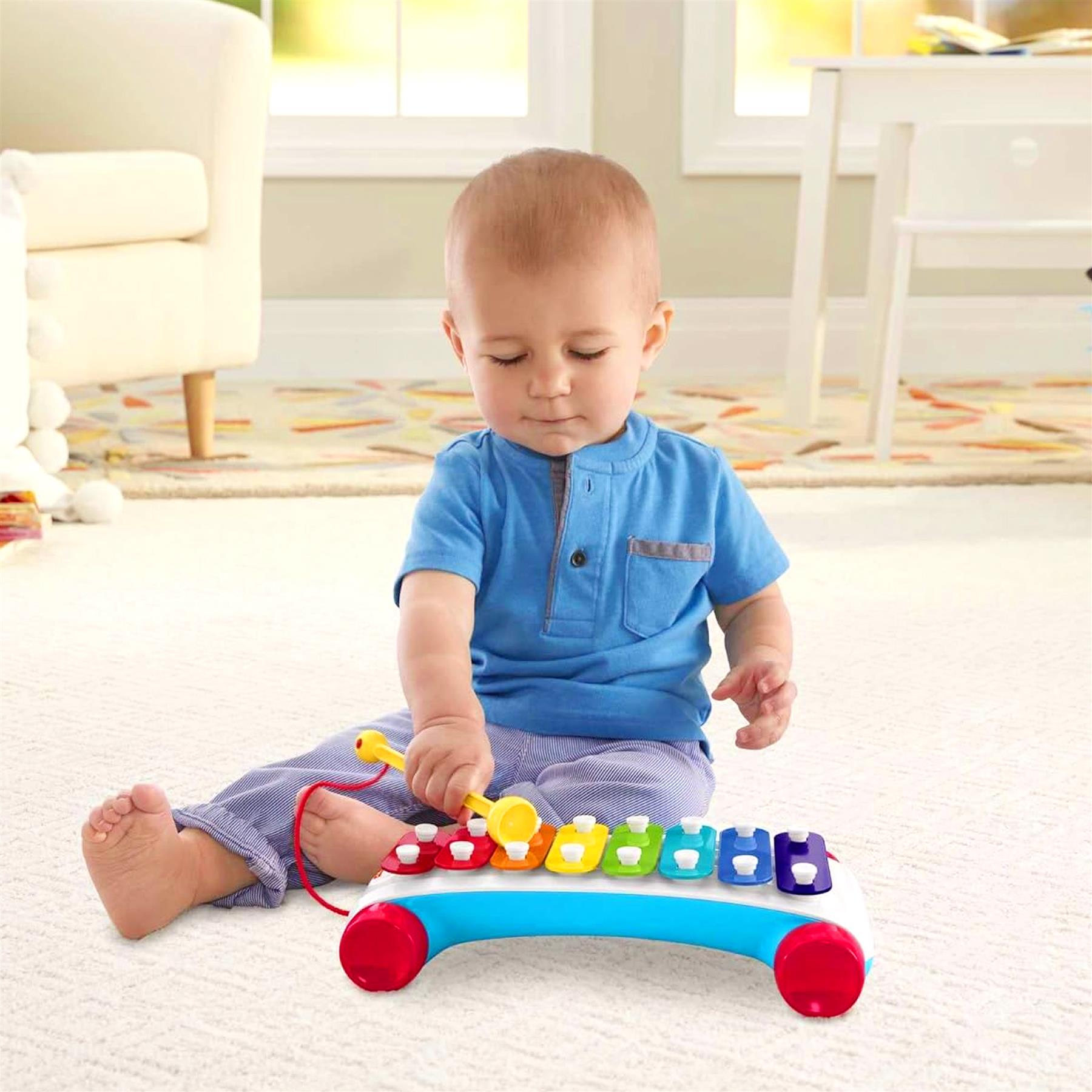 Toddler sits playing with a bright, colorful musical toy xylophone that has blue keys.