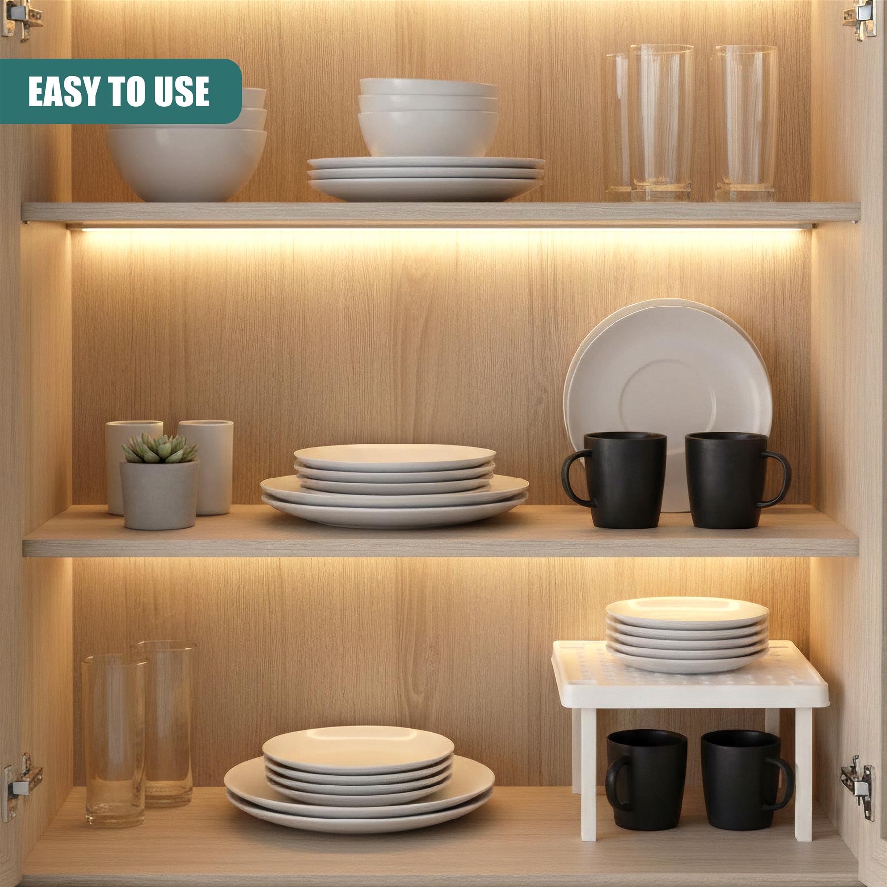 A wooden cabinet with multiple shelves, each holding various kitchenware items. The top shelf has a white bowl, a stack of plates, and two glasses. The middle shelf has a plate, two mugs, and a small plant in a pot. The bottom shelf has a stack of plates, two mugs, and a small table with two mugs underneath. The cabinet has a light wood tone and has several small lights inside, creating a warm and cozy atmosphere. The overall design is modern and minimalist, with clean lines and a focu… - The Magic Toy Shop