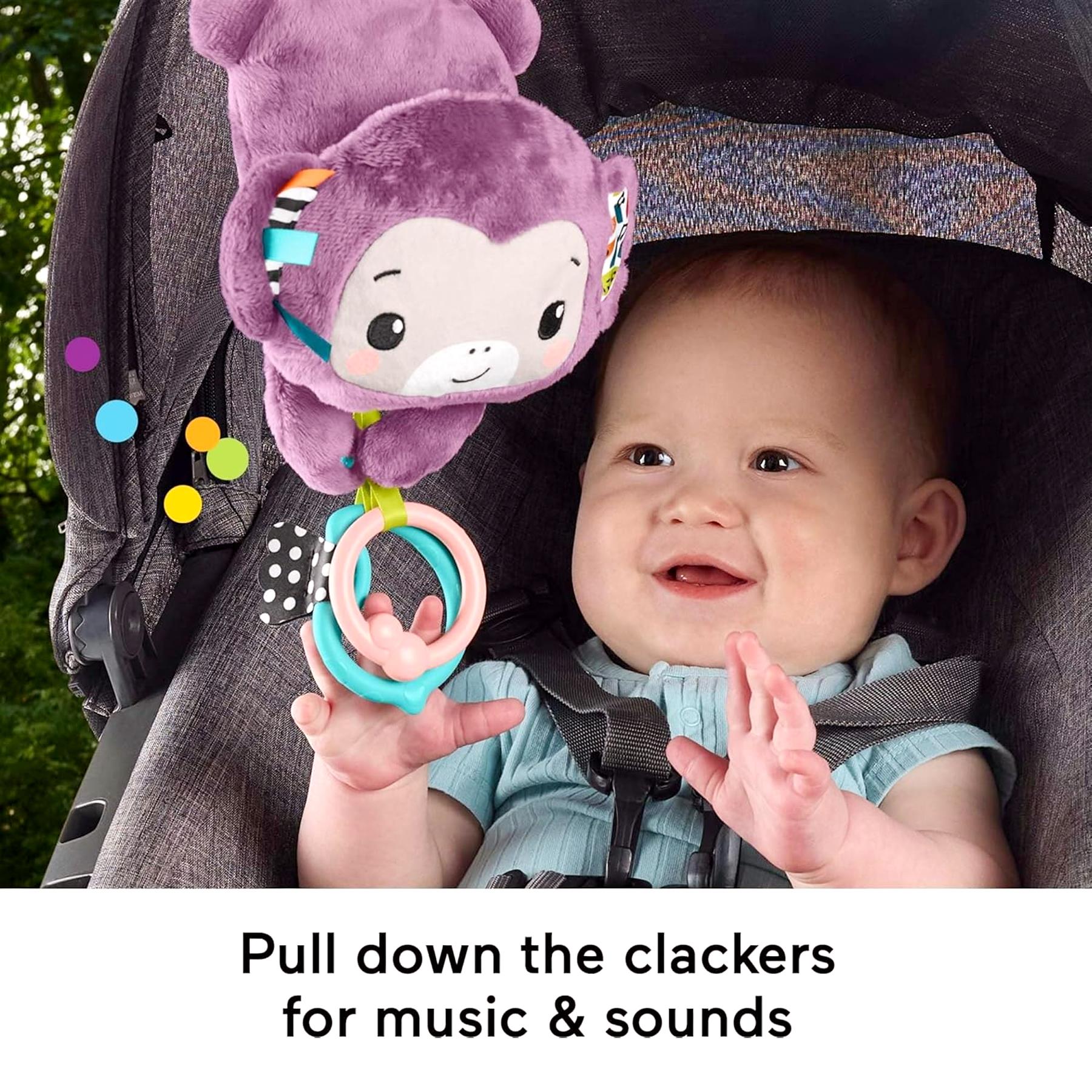 A plush purple monkey toy hangs from the stroller and has dangling plastic clackers for baby play.