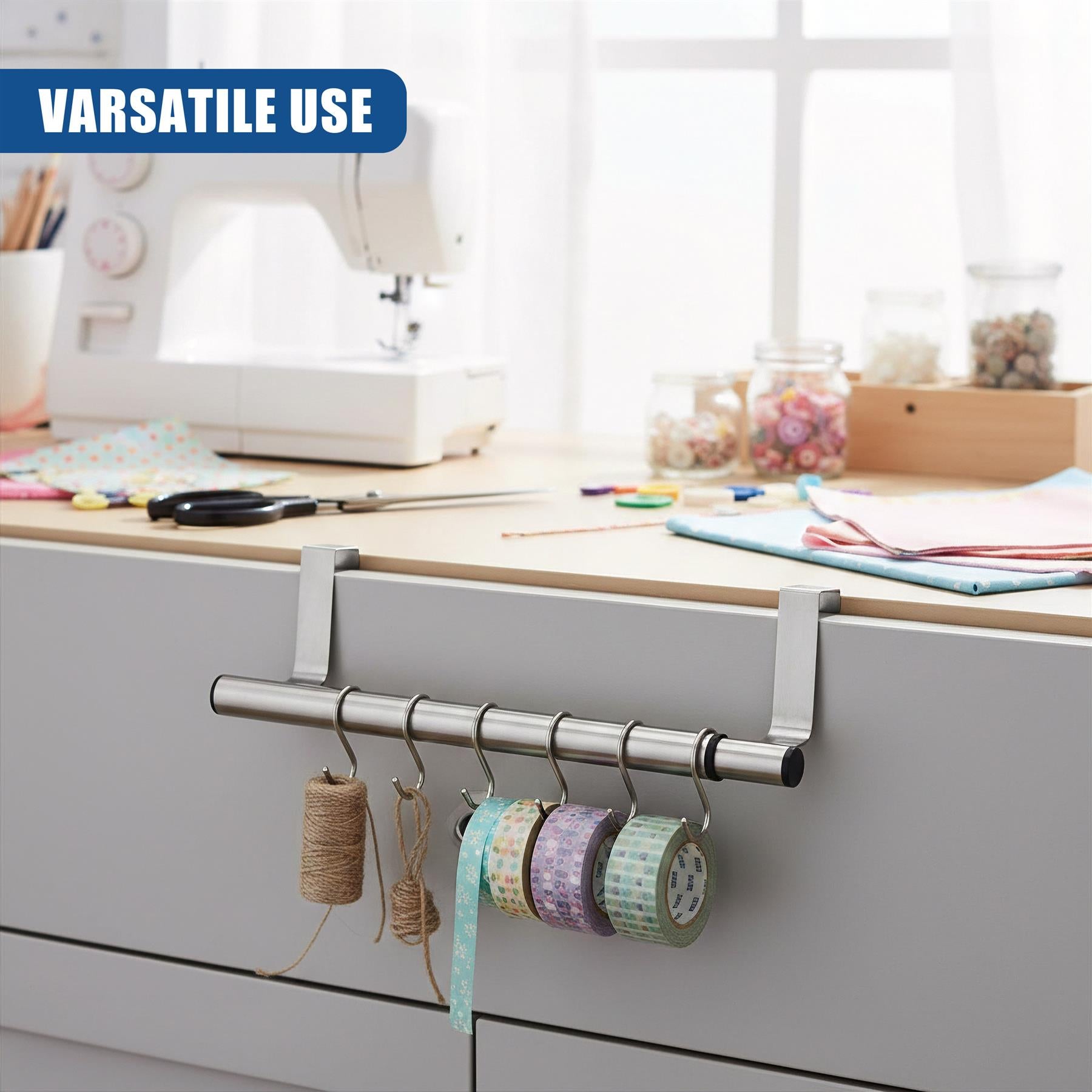 Metal rail hardware mounted on a cabinet, displaying several hanging spools of ribbon and thread.