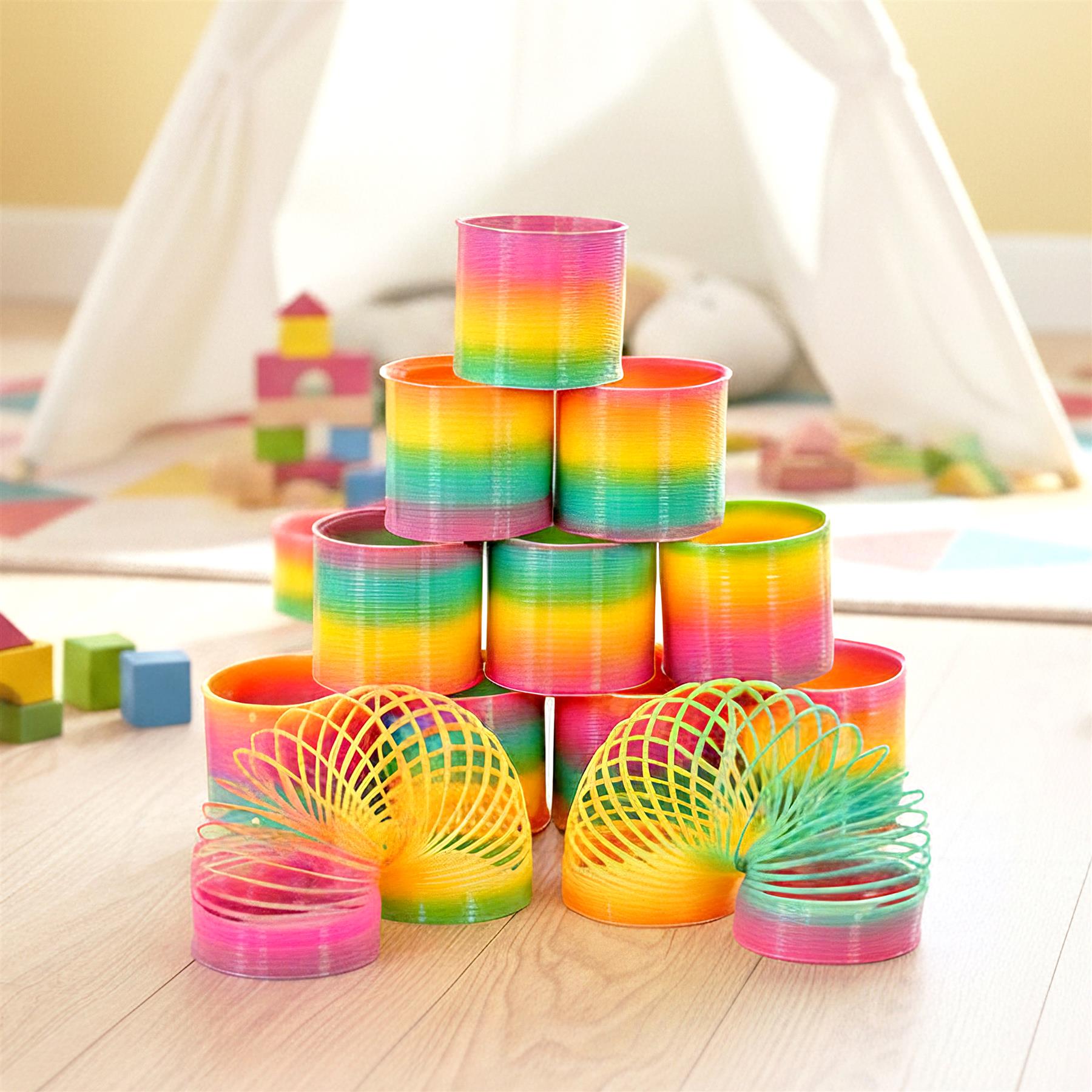 Assorted rainbow-colored spring coils and cylindrical stacks arranged on a light wooden surface.