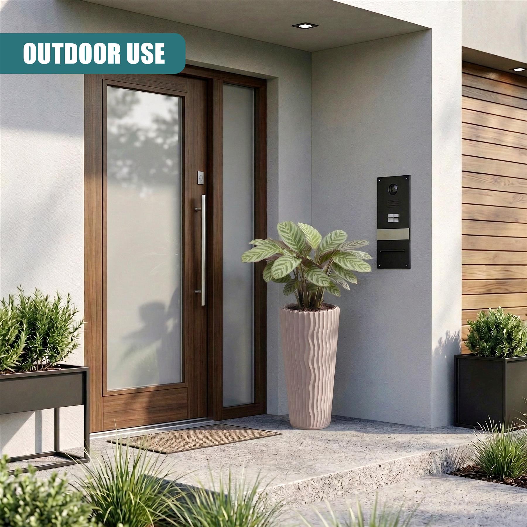 A tall, ribbed beige planter containing healthy green foliage placed near a modern front door.