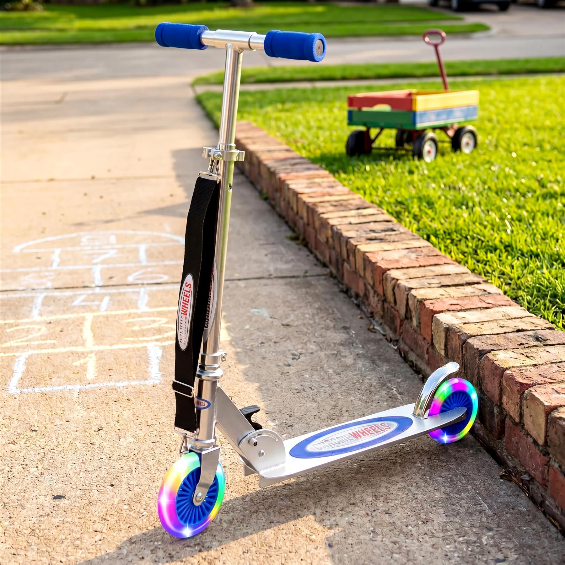 Blue and silver kids' scooter with blue handlebars rests on concrete next to a brick curb.