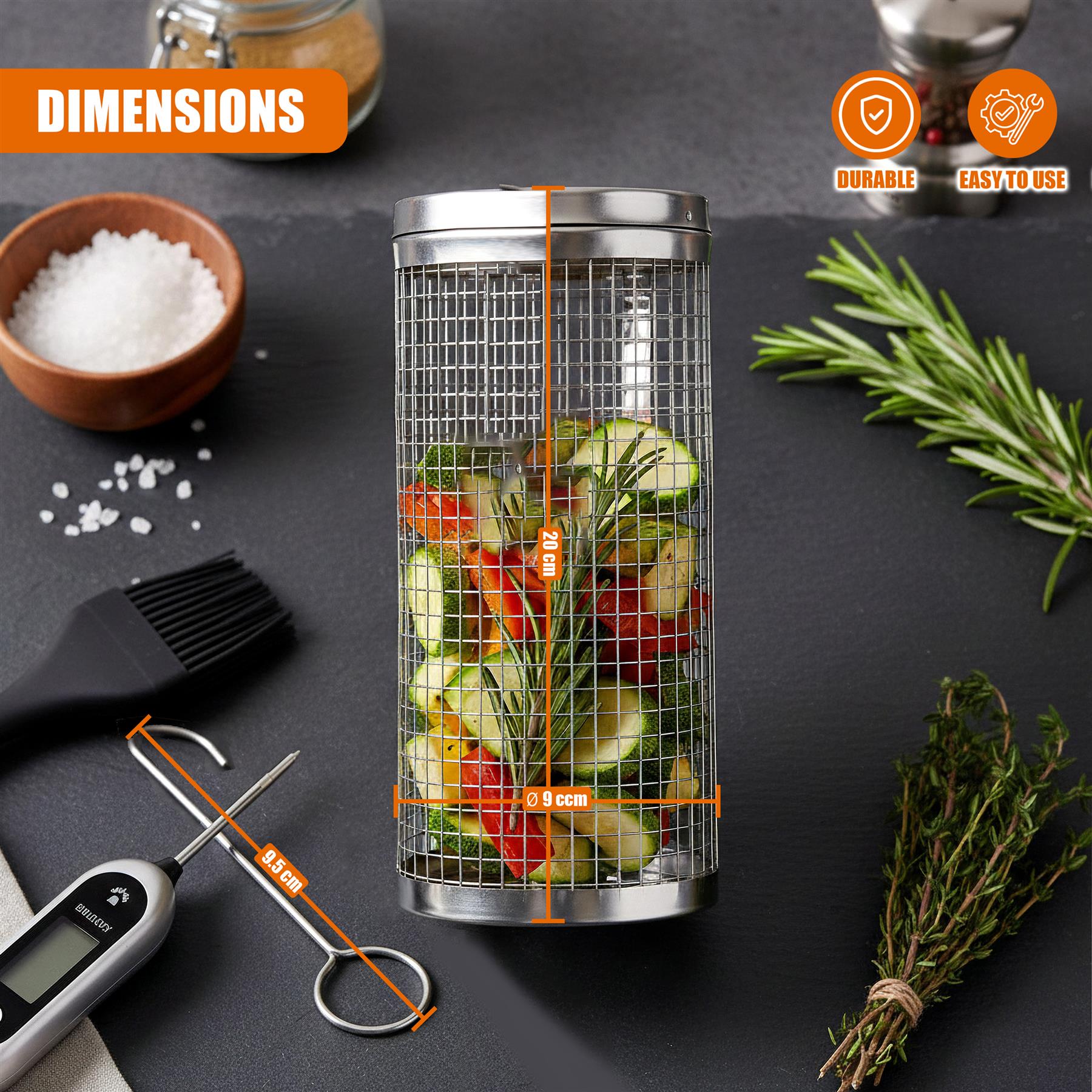 Stainless steel grilling basket containing sliced zucchini, tomatoes, and various kitchen tools.