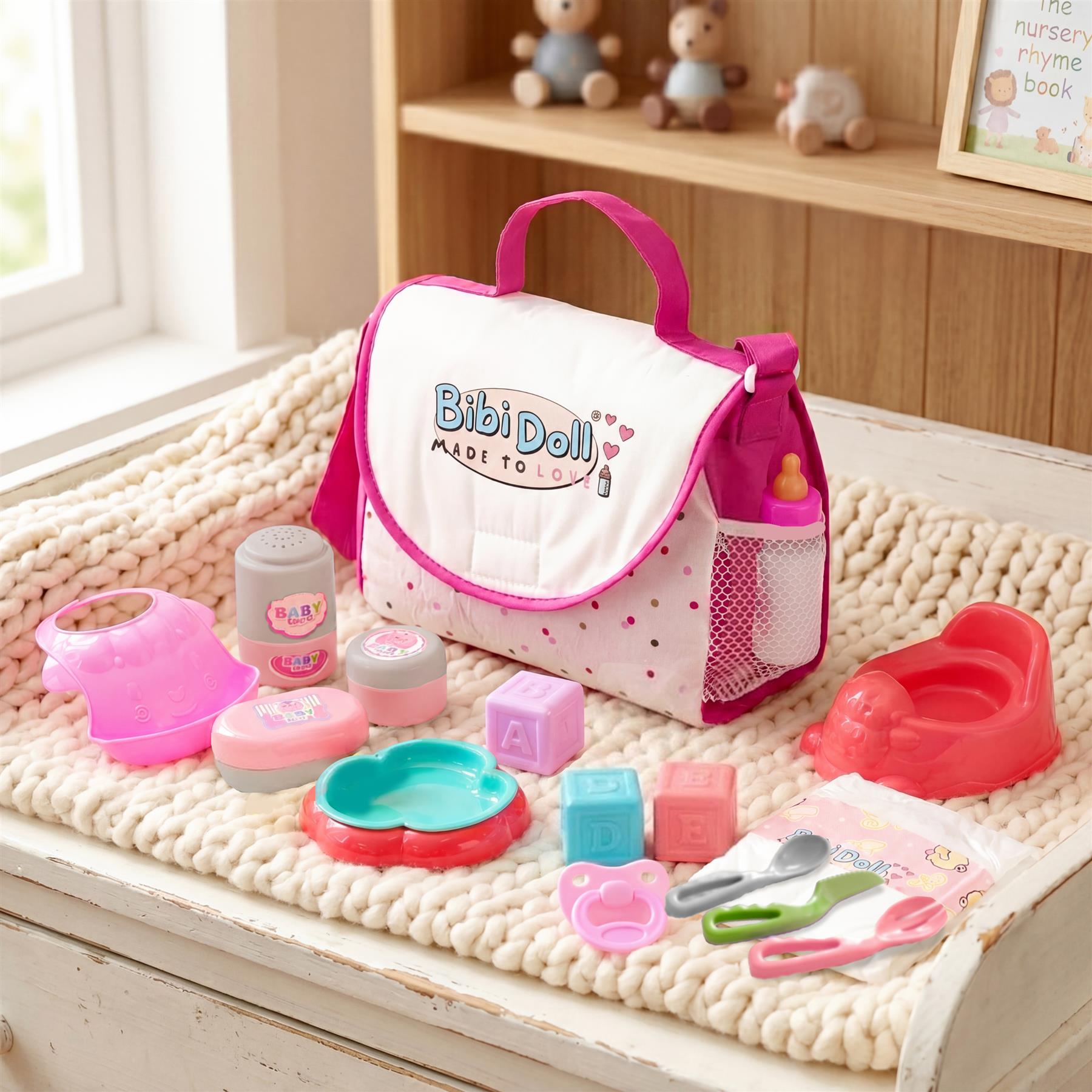 A pink doll changing bag displays with plastic accessories, dishes, and bath toys laid out.
