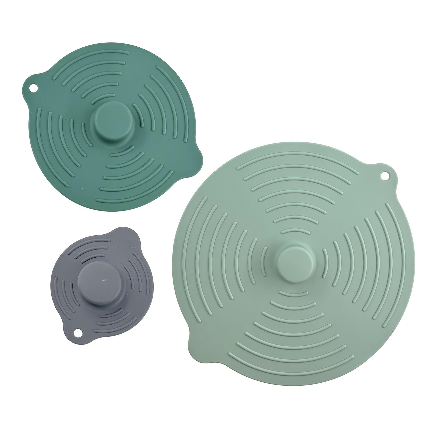 Three circular silicone food covers in different shades of green, featuring concentric ridges and central knobs.