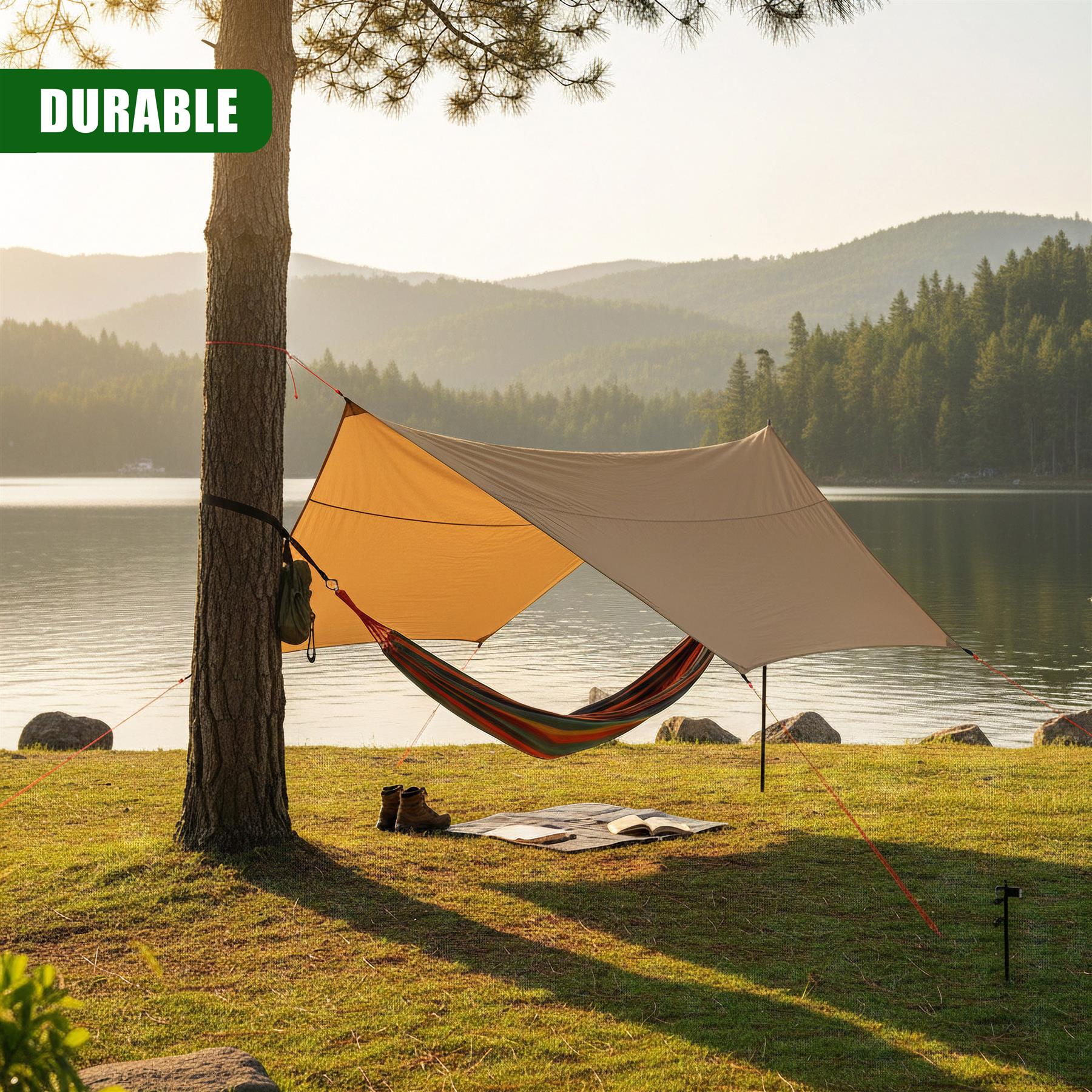 Two colored tarps and a hammock shelter are suspended between poles near a lake.