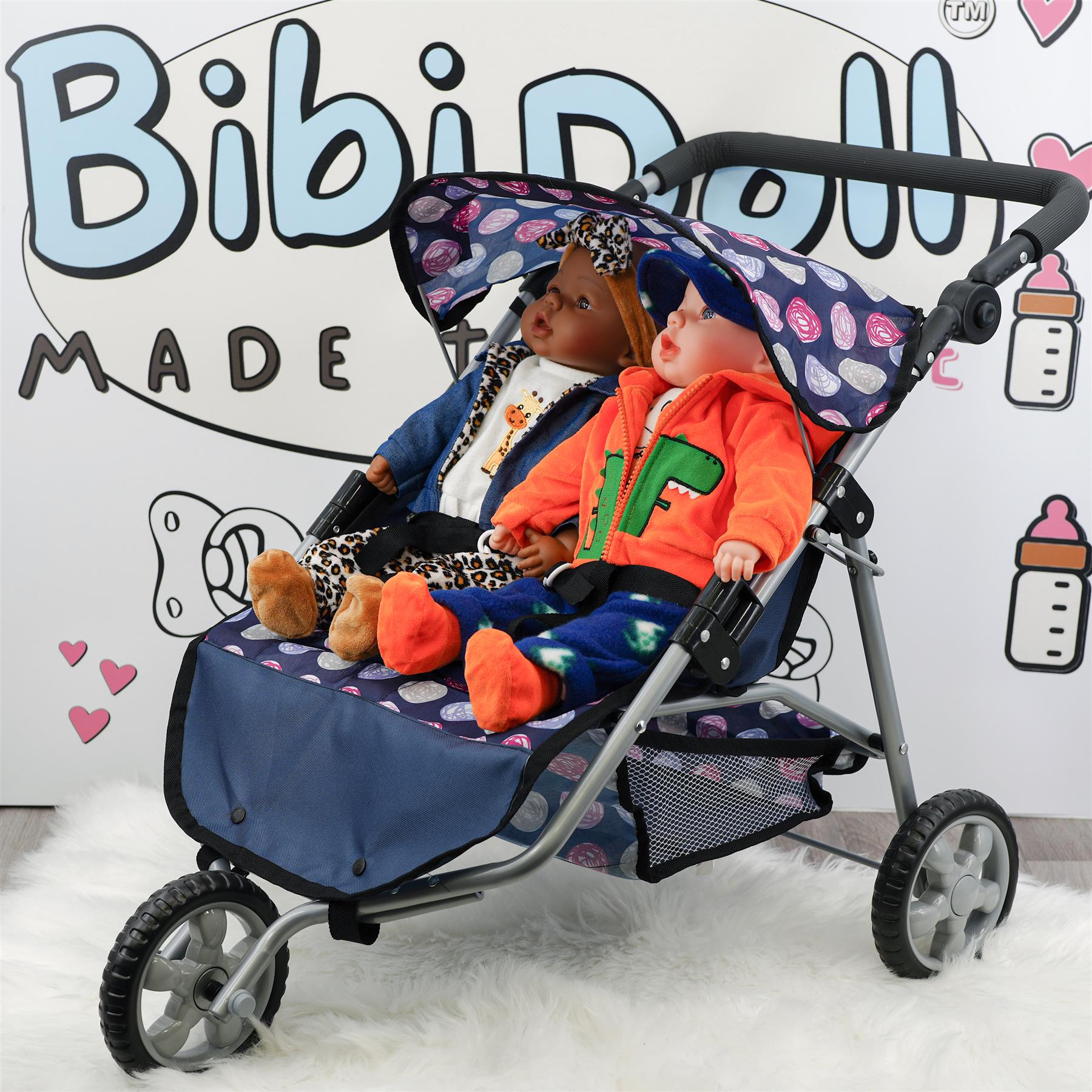 Two dolls dressed in outfits sit side-by-side in a blue and patterned pushchair.
