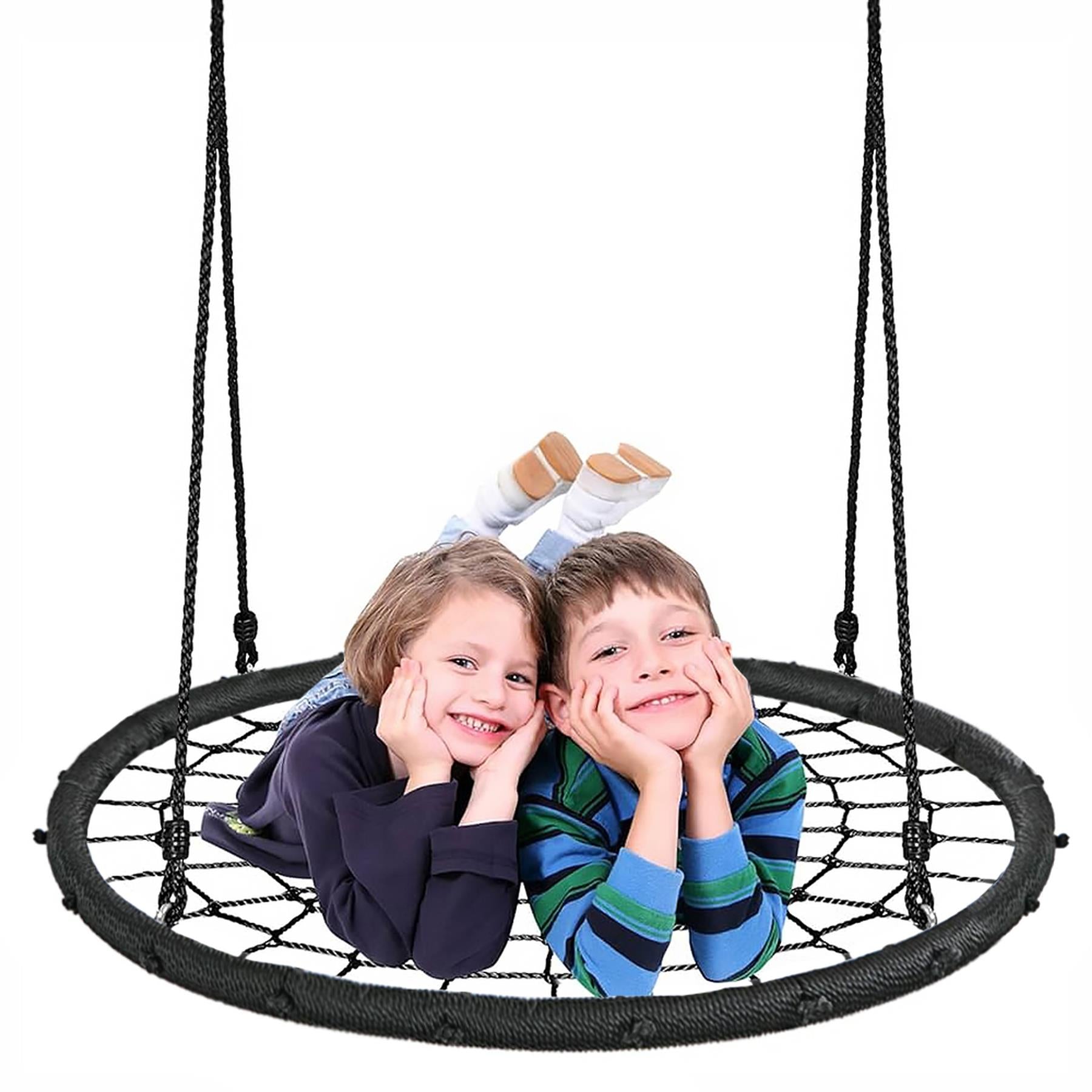 Two smiling children sit in a black, woven, hanging outdoor nest swing.