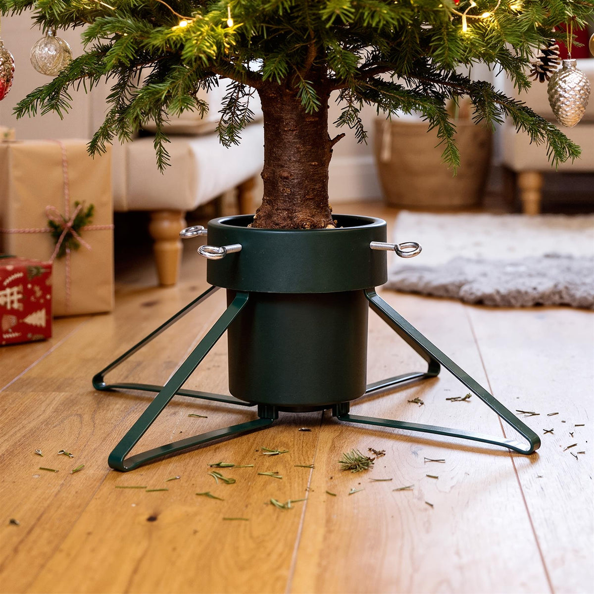Green metal Christmas tree stand with a real tree and festive decorations