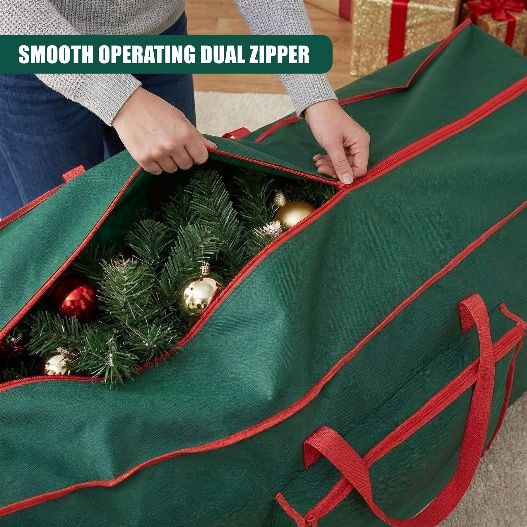 A person is opening a large green storage bag with red trim. The bag is filled with Christmas tree branches and ornaments. The person is holding the bag open with both hands, revealing the contents. The background is a hardwood floor with a white area rug and a few presents in the distance. - The Magic Toy Shop
