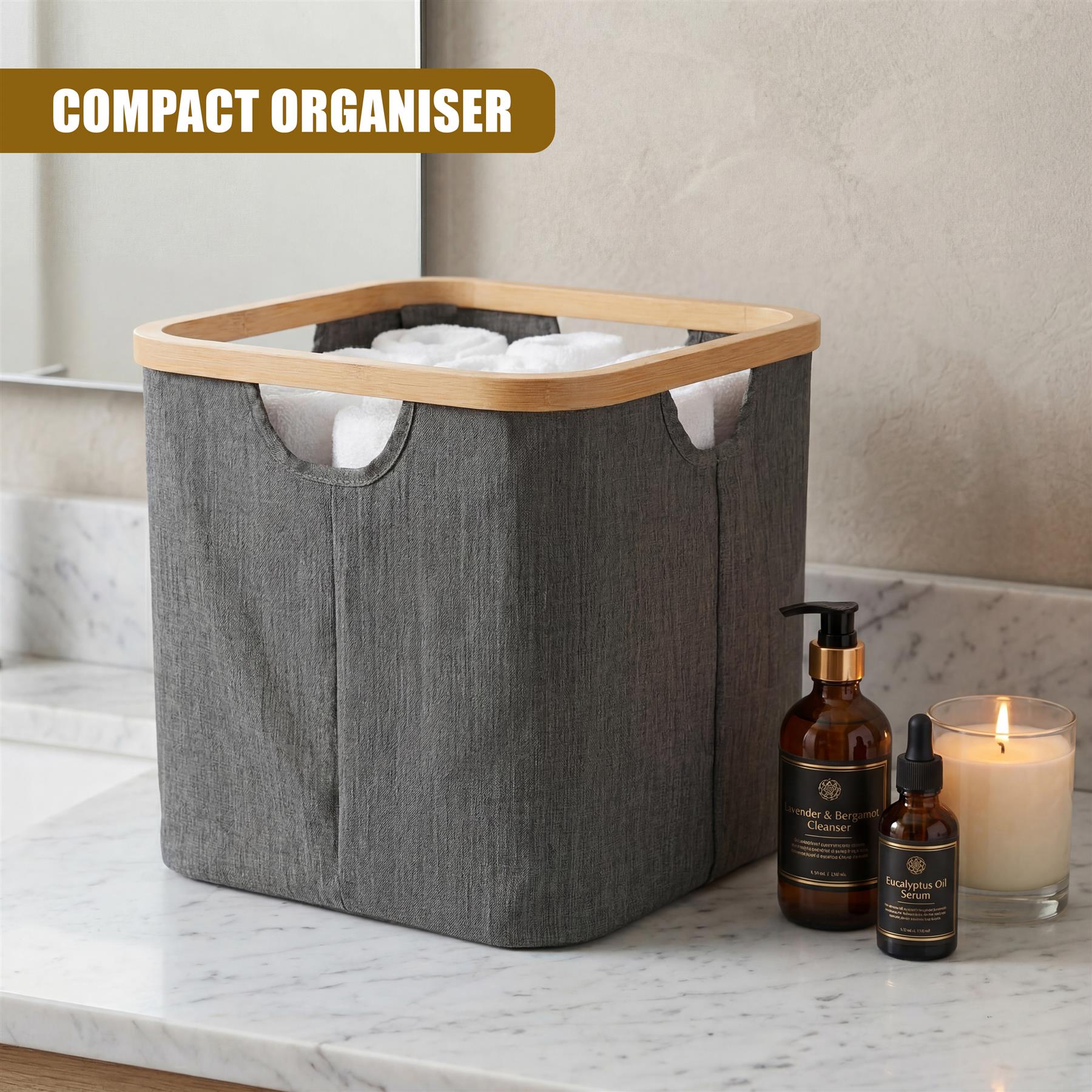 A gray collapsible hamper sits next to toiletries and a lit candle on a marble counter.
