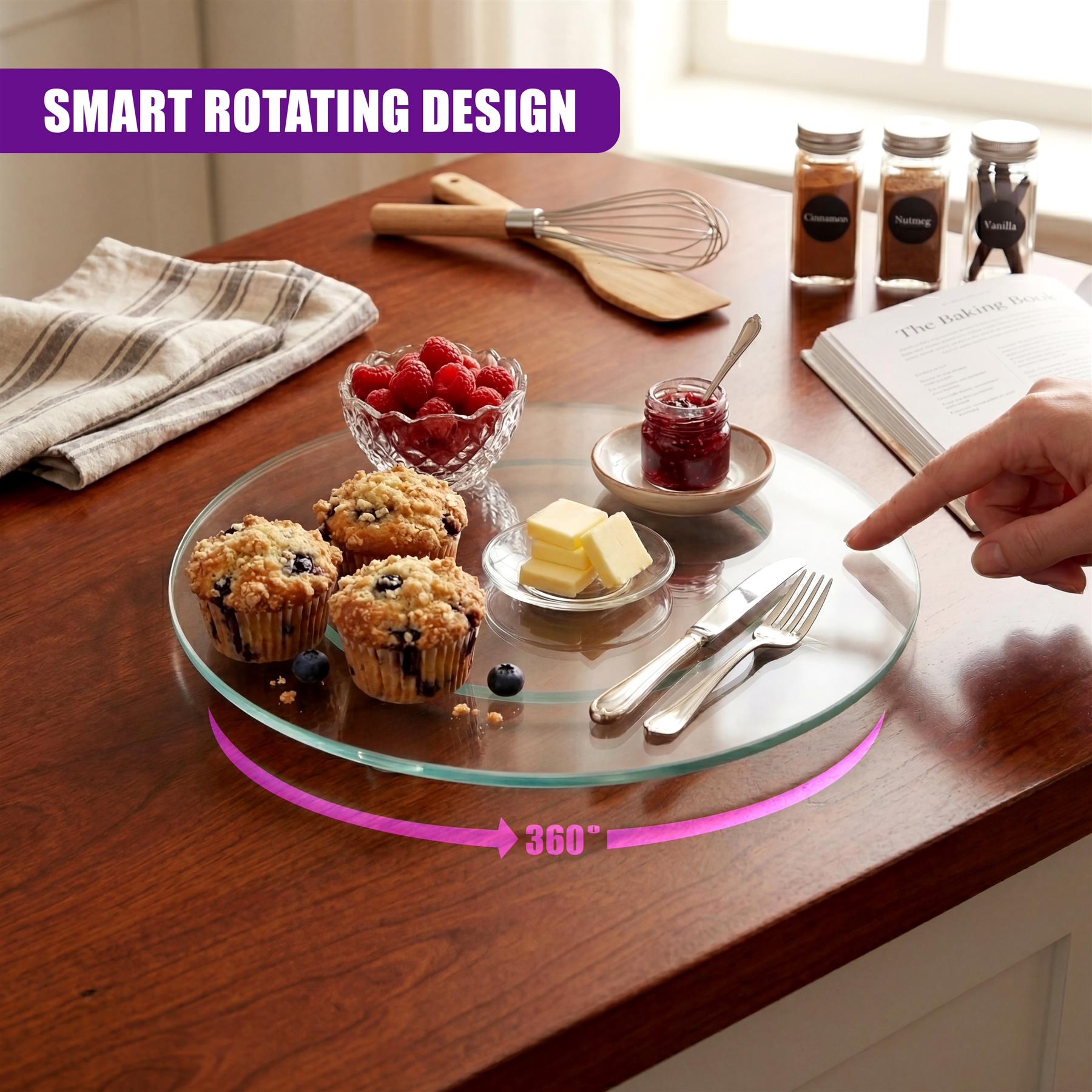 Glass turntable displayed with cupcakes, butter, jam, and serving utensils on a wooden kitchen surface.