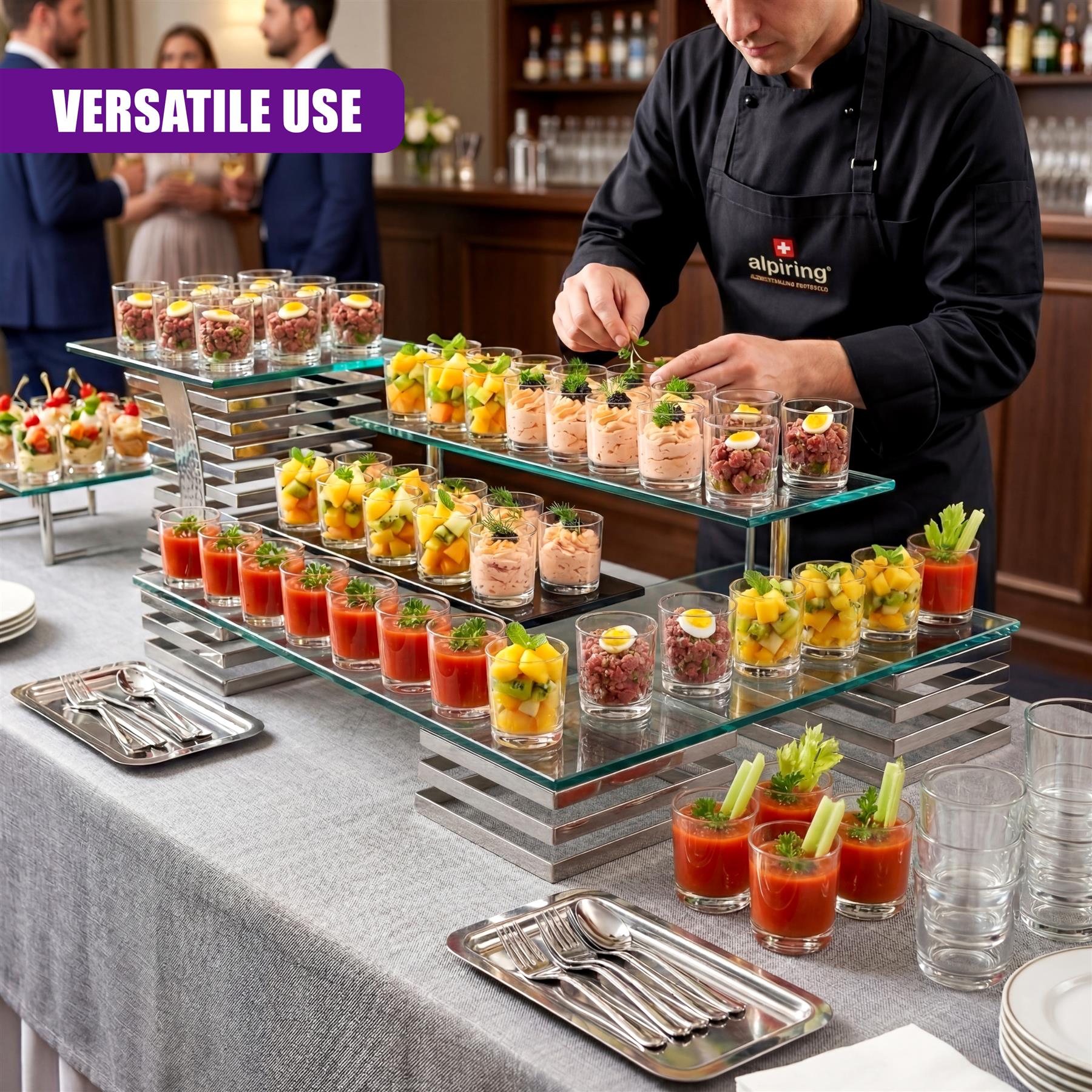 Glass tiered display stand holding multiple small servings, mini desserts, and shot glasses.