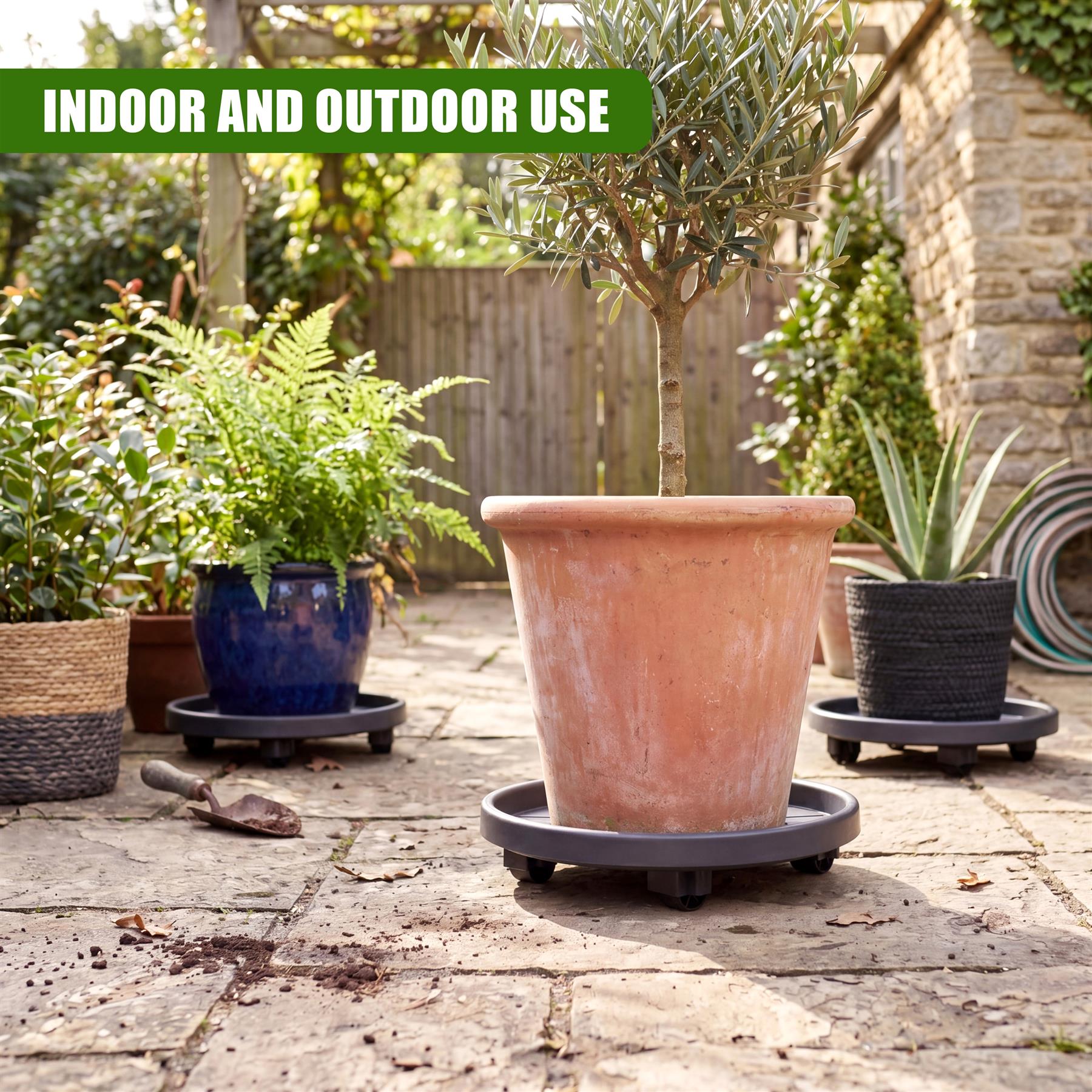 A large terracotta flower pot rests on a black, wheeled circular plant caddy outdoors.