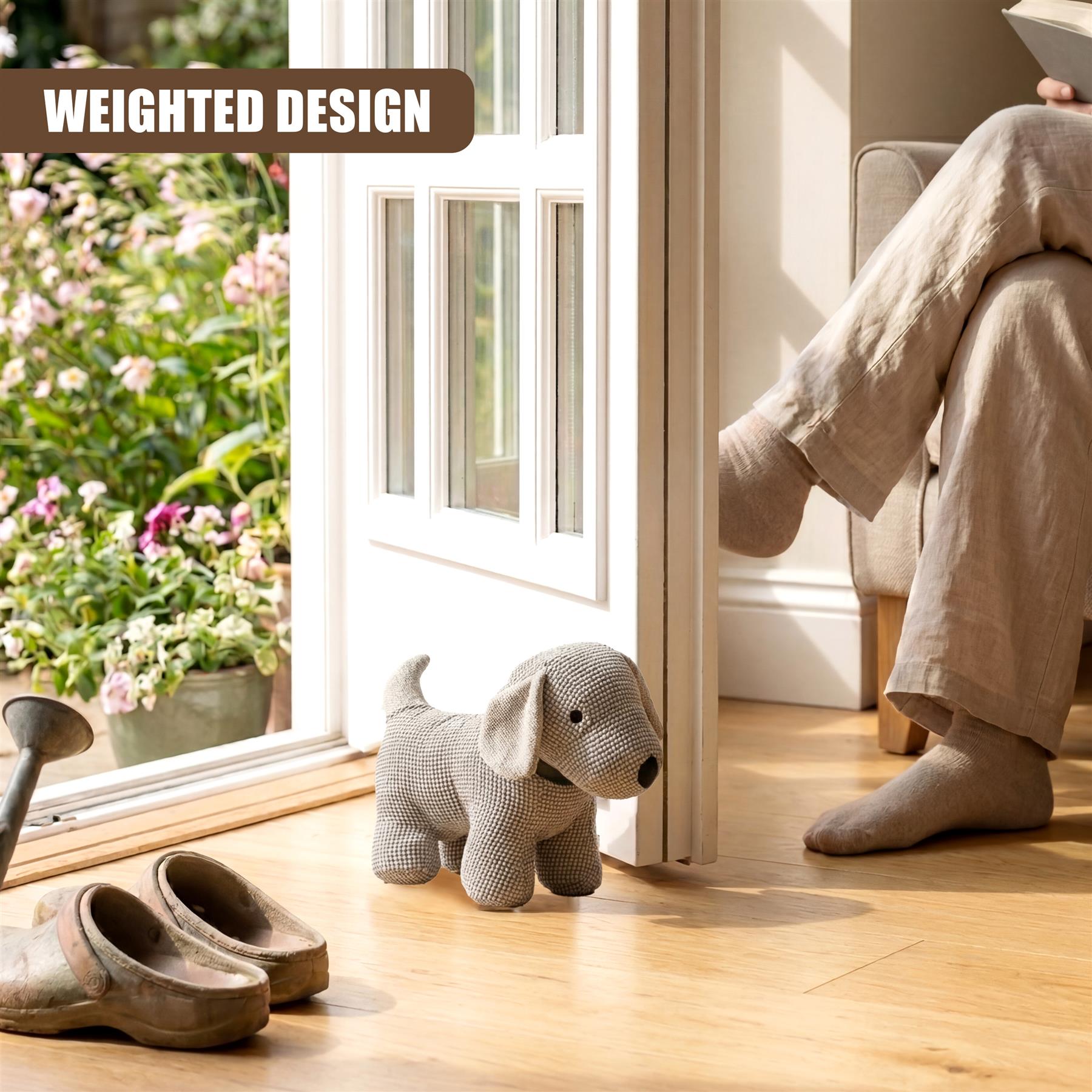 Knitted gray dog door stopper and matching paw prints rest on a light wood floor.