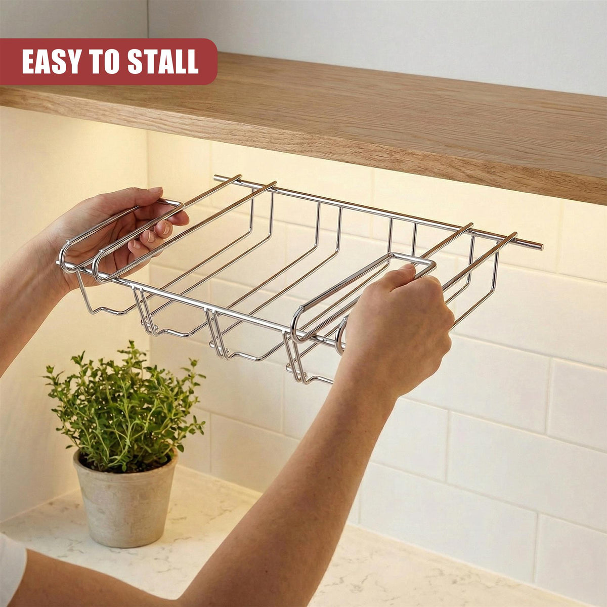 A person installs the GEEZY under shelf wine glass rack on a kitchen shelf with a plant