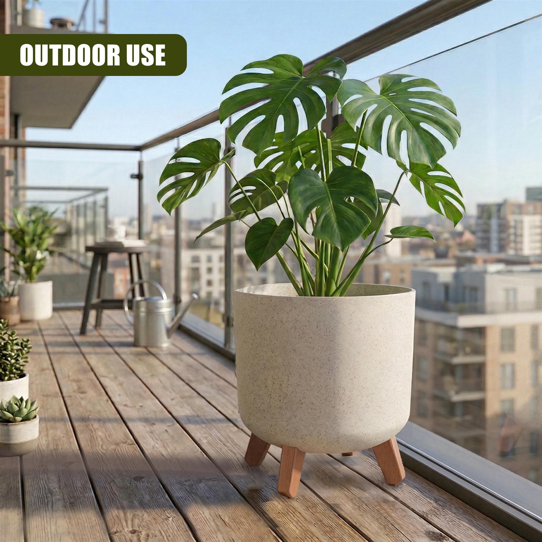 Large potted plant on wooden deck featuring a light-colored pot with wooden legs and lush green foliage.