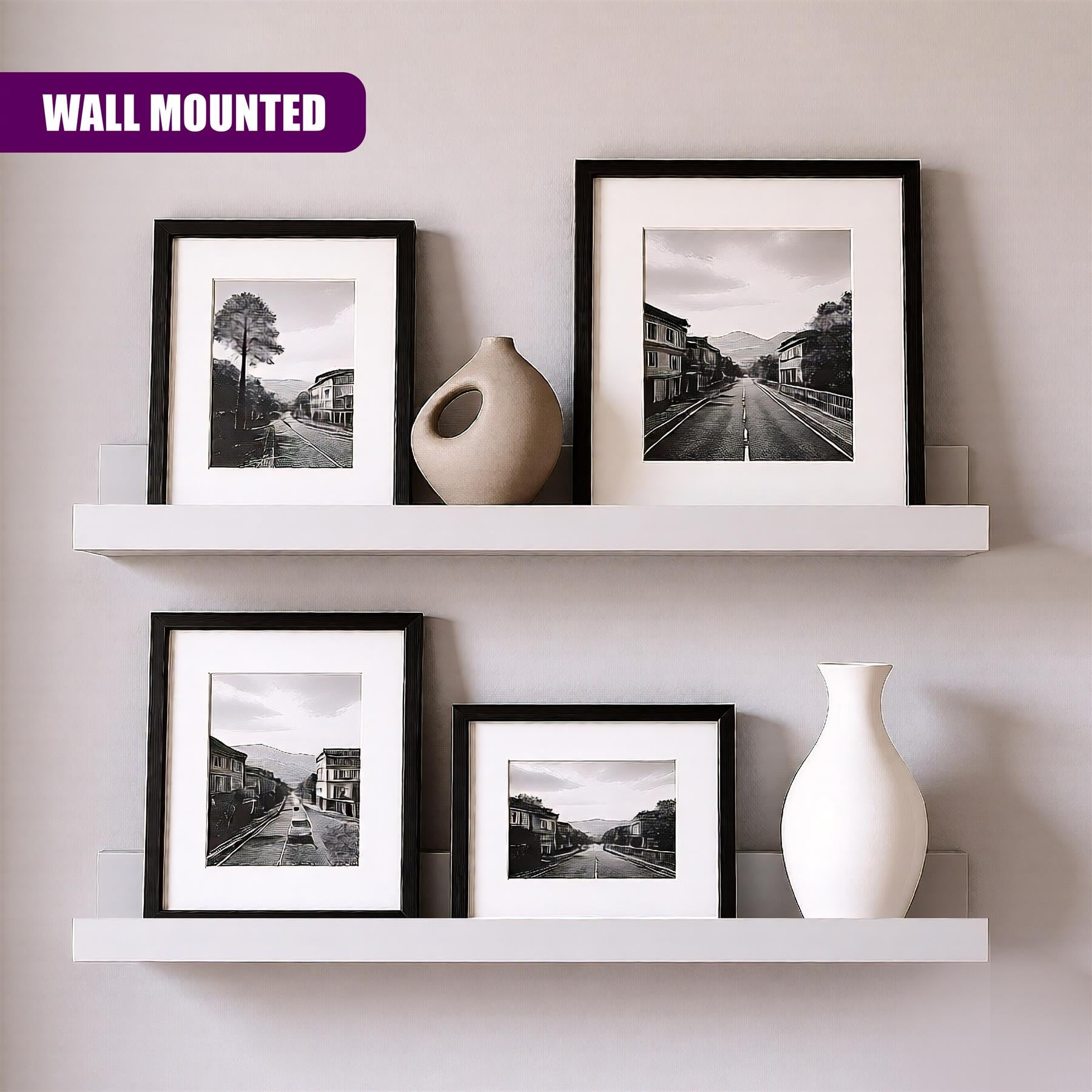 A wall-mounted shelf with four black-framed photos of various city streets, each in a different size, and three white vases of different shapes and sizes. - The Magic Toy Shop