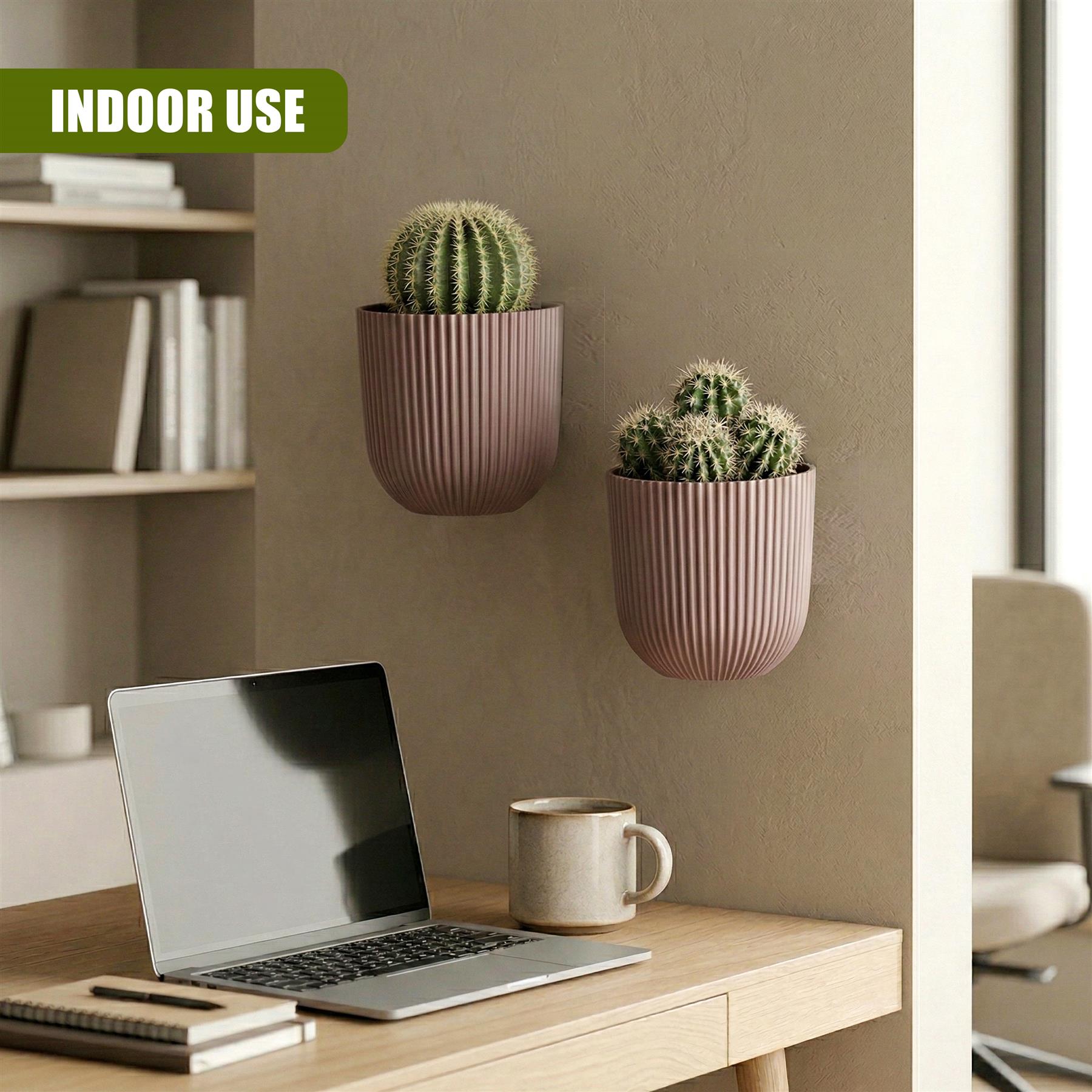 Two matching, dusty rose planters holding small cacti sit against a wooden wall.