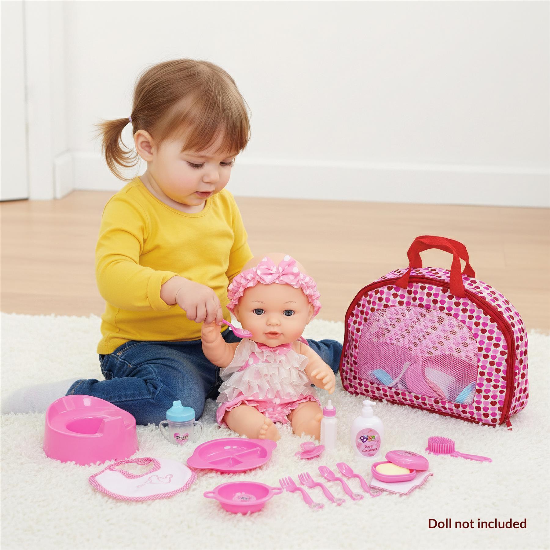 A young girl sits on the floor with a baby doll, surrounded by a pink play set. The girl holds a pink spoon, feeding the doll. A pink play set, including a high chair, is in front of them. A pink lunch box and other toys are also visible. - The Magic Toy Shop