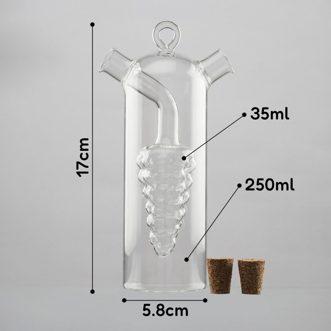 A clear glass oil and vinegar dispenser with a unique grape cluster design, featuring two spouts and measurements labeled for 35ml and 250ml capacities. The height is 17cm and width is 5.8cm, accompanied by two cork stoppers. Ideal for kitchen use. Available at themagictoyshop.