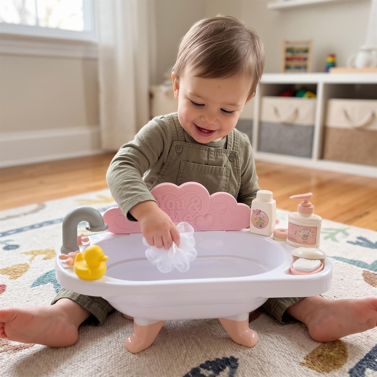 A baby plays with a pink doll bath set with accessories, including a duck and bubble soap