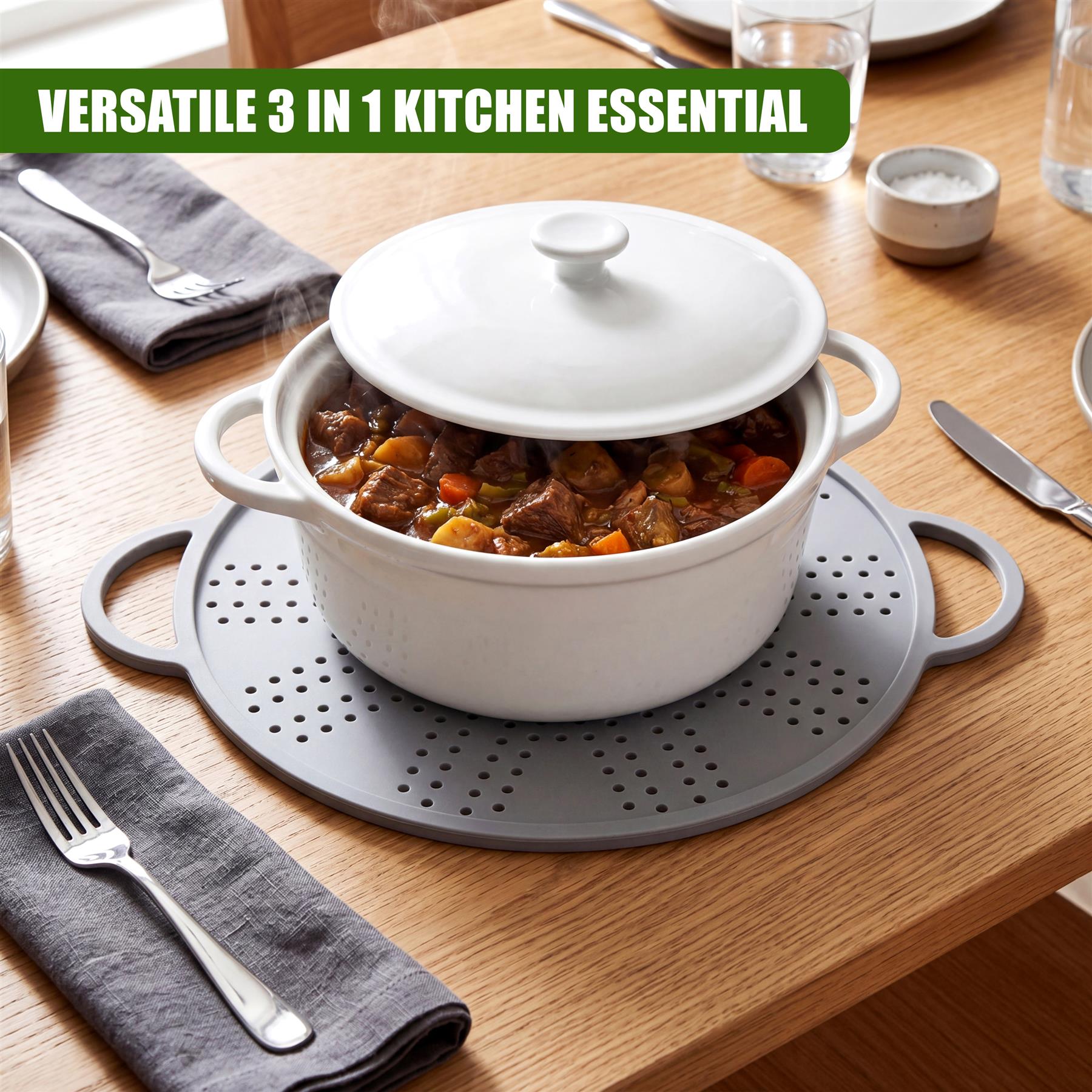 White cooking pot containing food rests on a gray perforated draining plate on a wooden table.