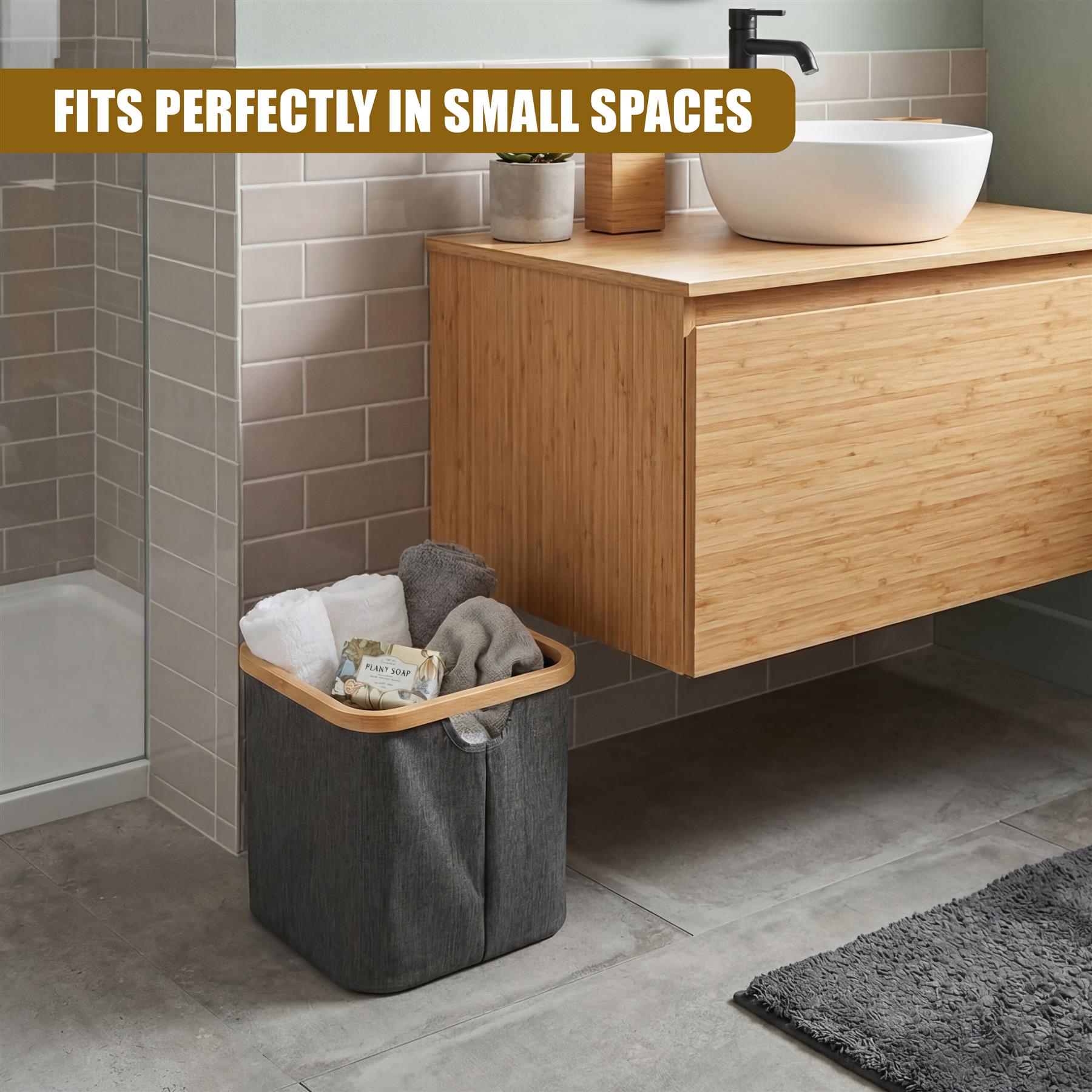 Gray fabric hamper containing folded white and gray textiles, resting on the floor of a bathroom.