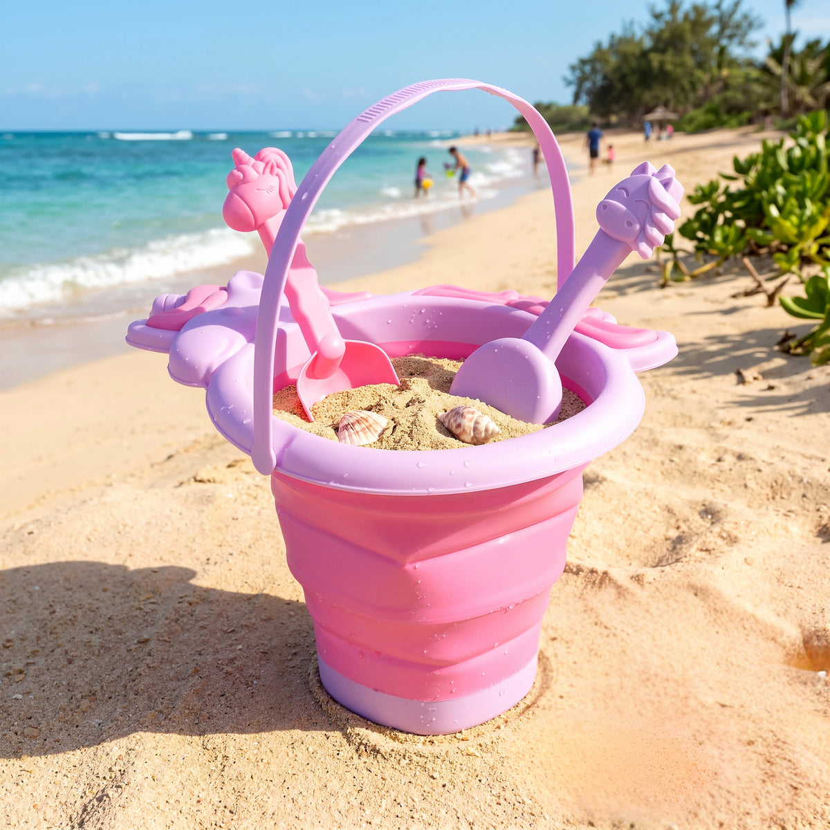 Pink bucket and spade set sits on a sandy beach with a blue ocean background