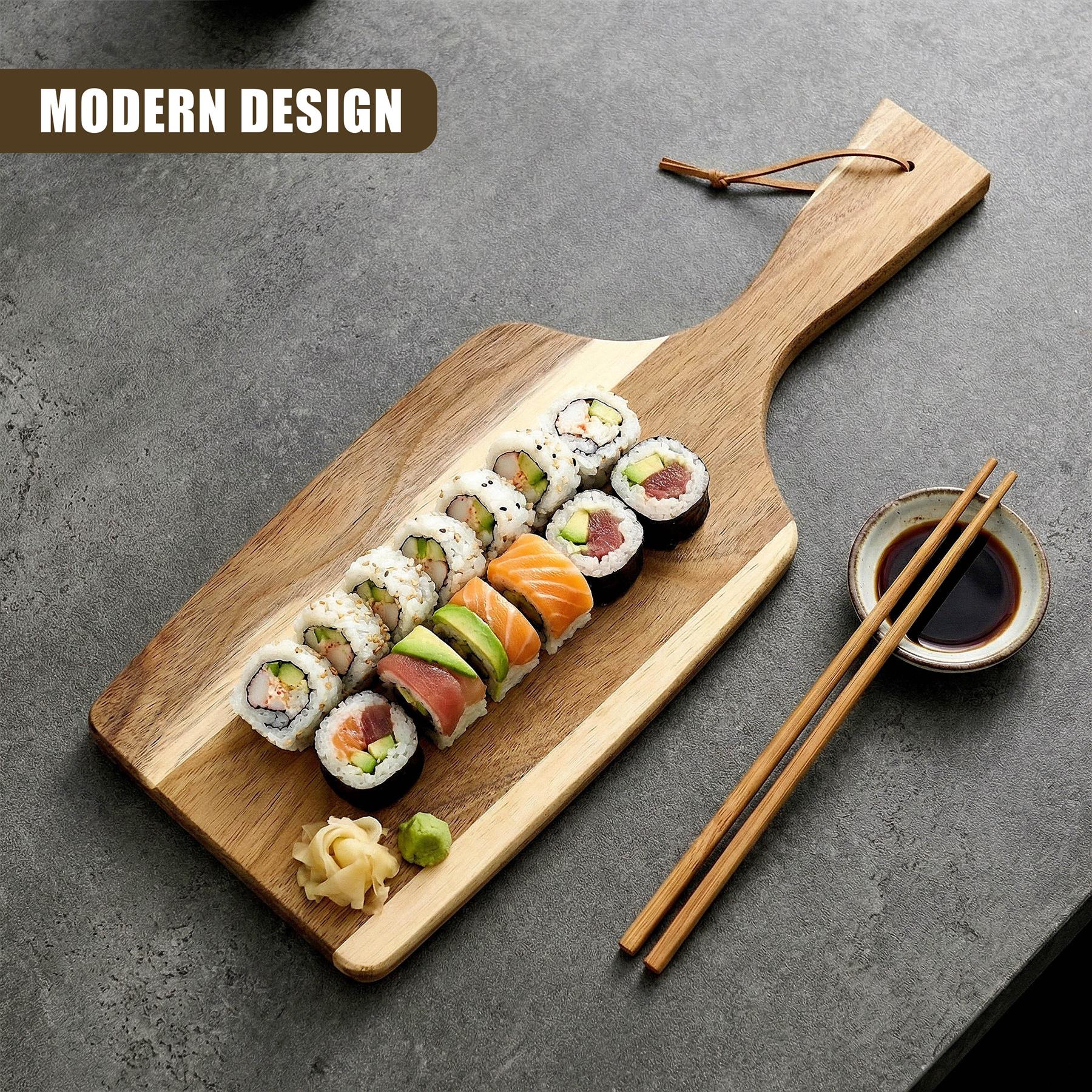 Wooden paddle board displaying sushi rolls, avocado slices, chopsticks, and small dipping sauce bowl.