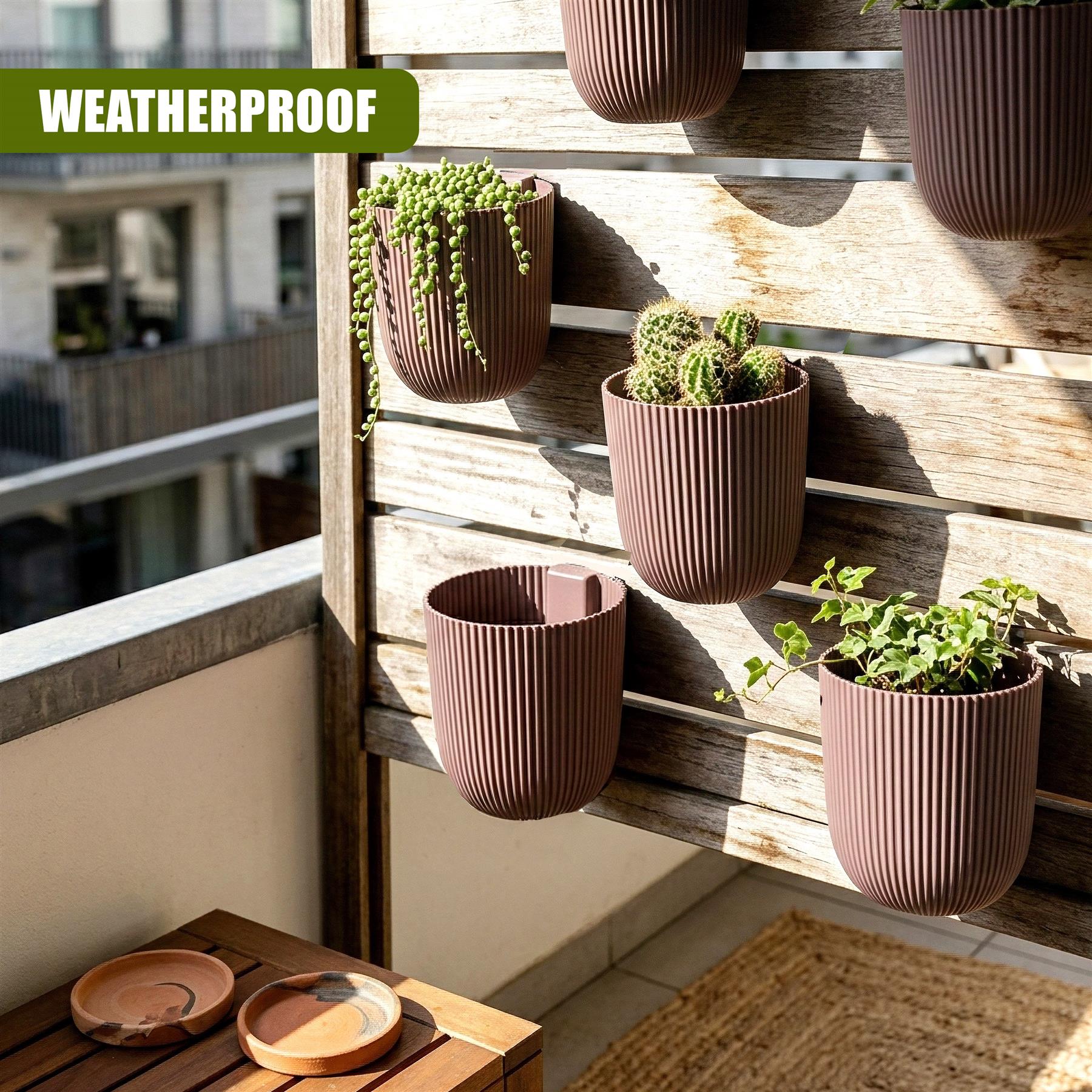 Three ribbed, brown planters filled with greenery are mounted on a wooden outdoor lattice wall.
