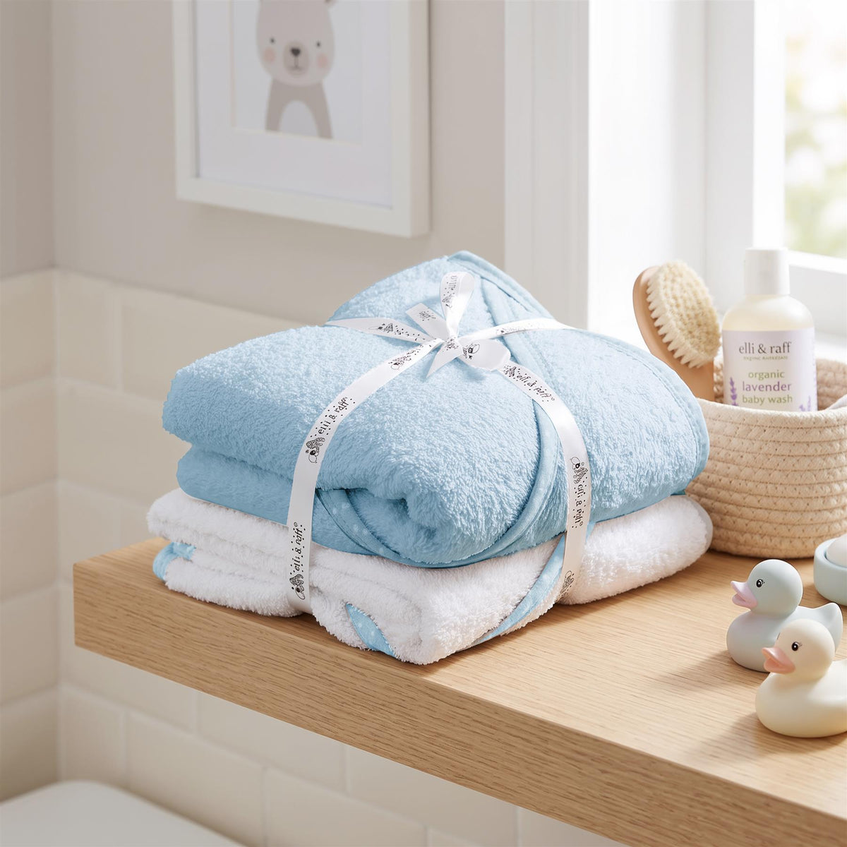 Two blue hooded baby towels from GEEZY are stacked together on a wooden shelf