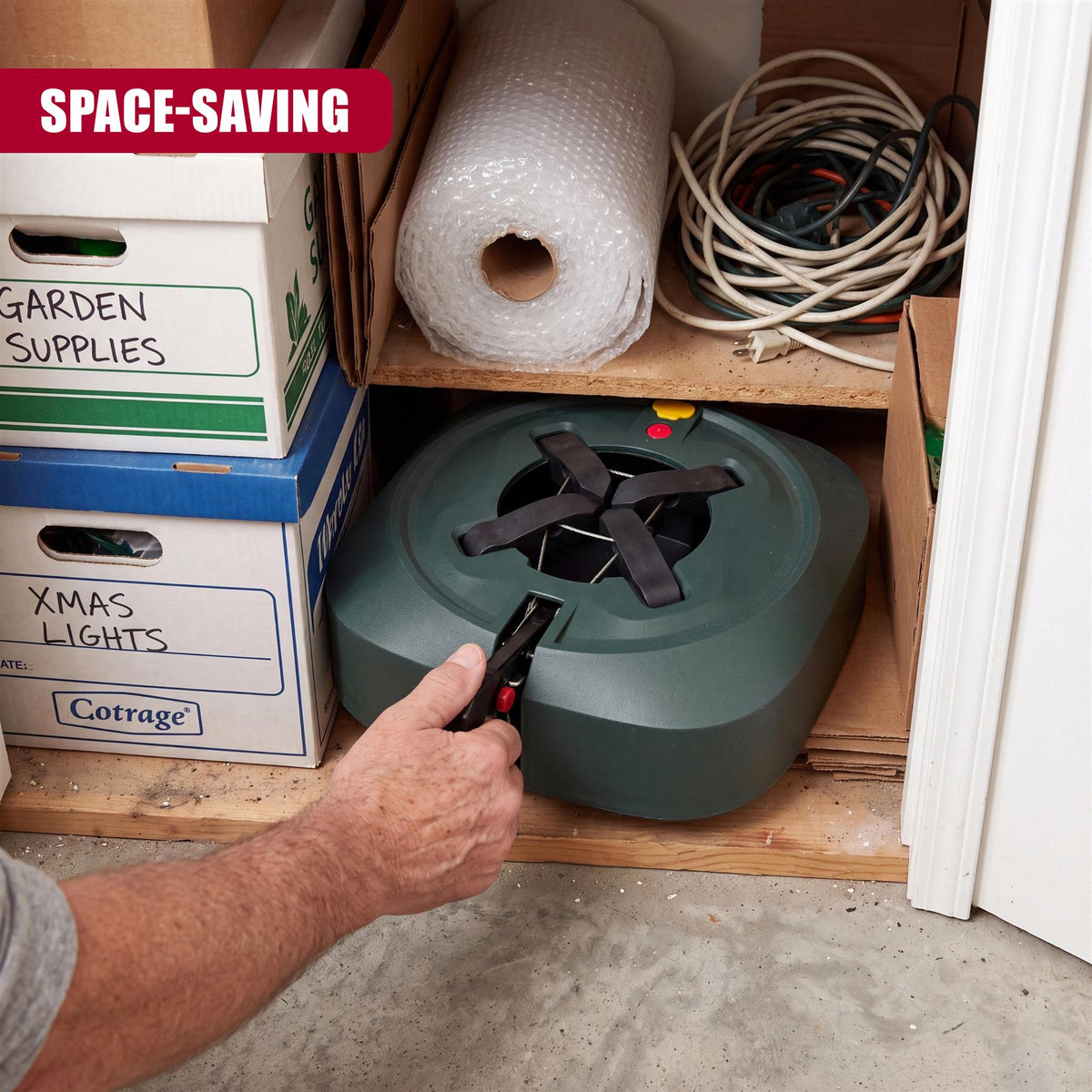 A man adjusts a green Christmas tree stand with a water reservoir, part of a storage space