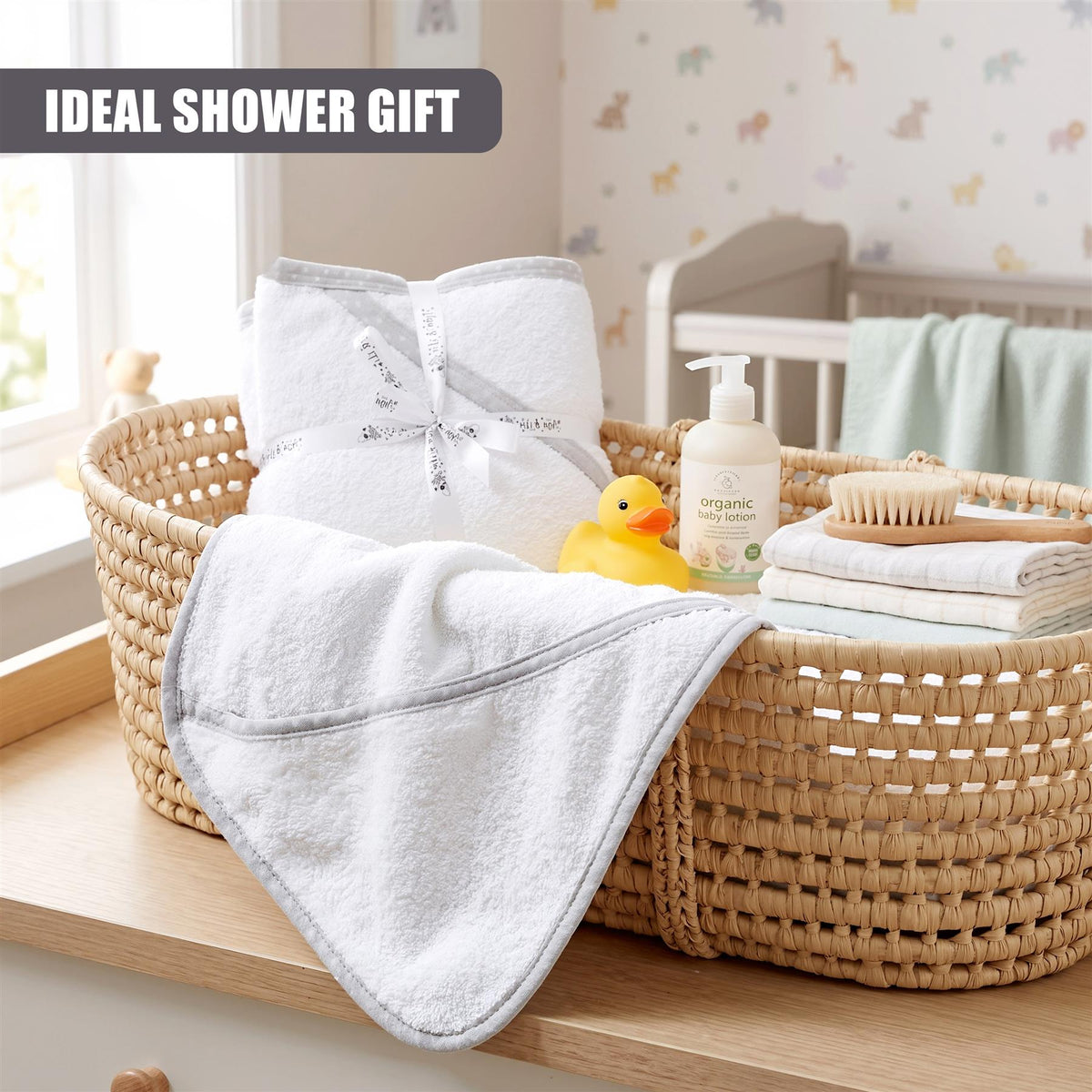 A woven basket contains two grey hooded baby towels and baby bath products, ideal for a baby shower gift