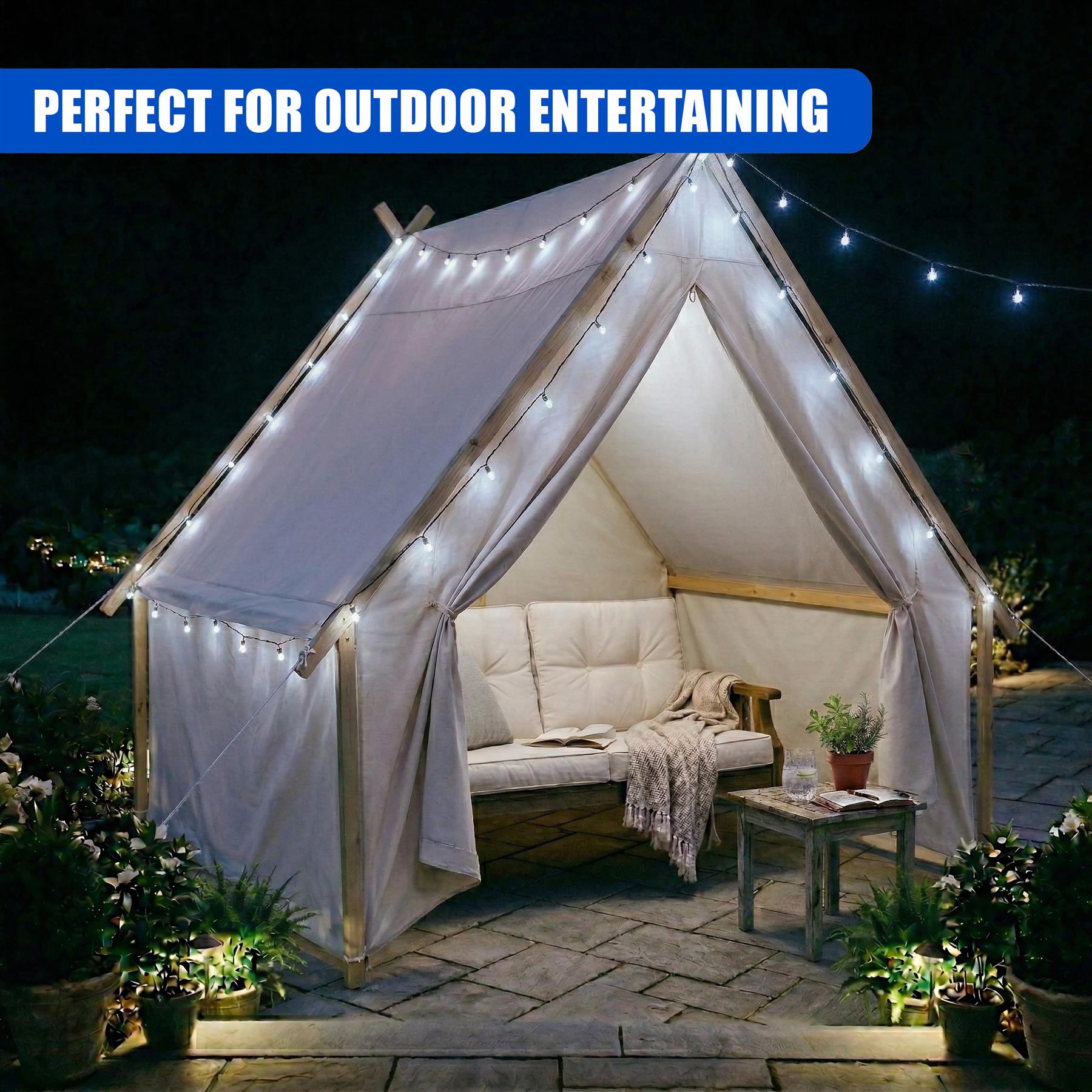 White peaked canopy illuminated by string lights, showing an inner cushioned bench and potted plants.