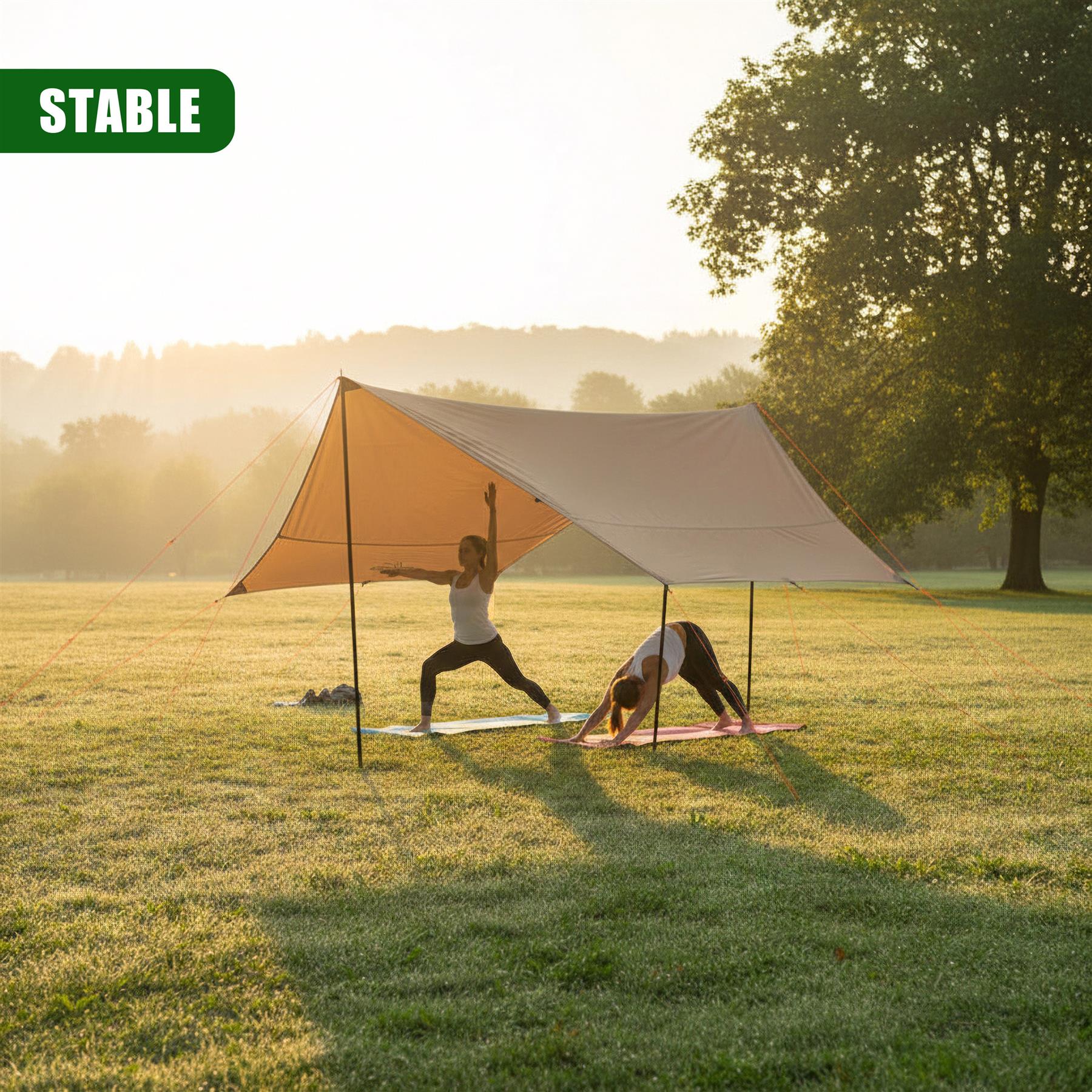 Two people perform yoga inside an open, light-colored camping tarp shelter set up on grass.