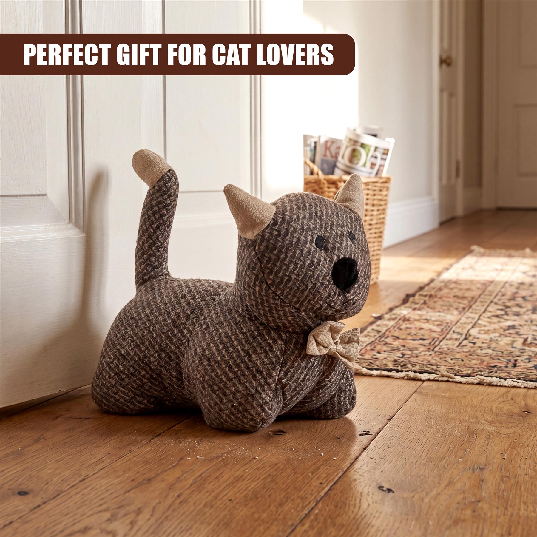 Plush, grey kitten novelty door stopper toy with bow rests on wooden floorboards.