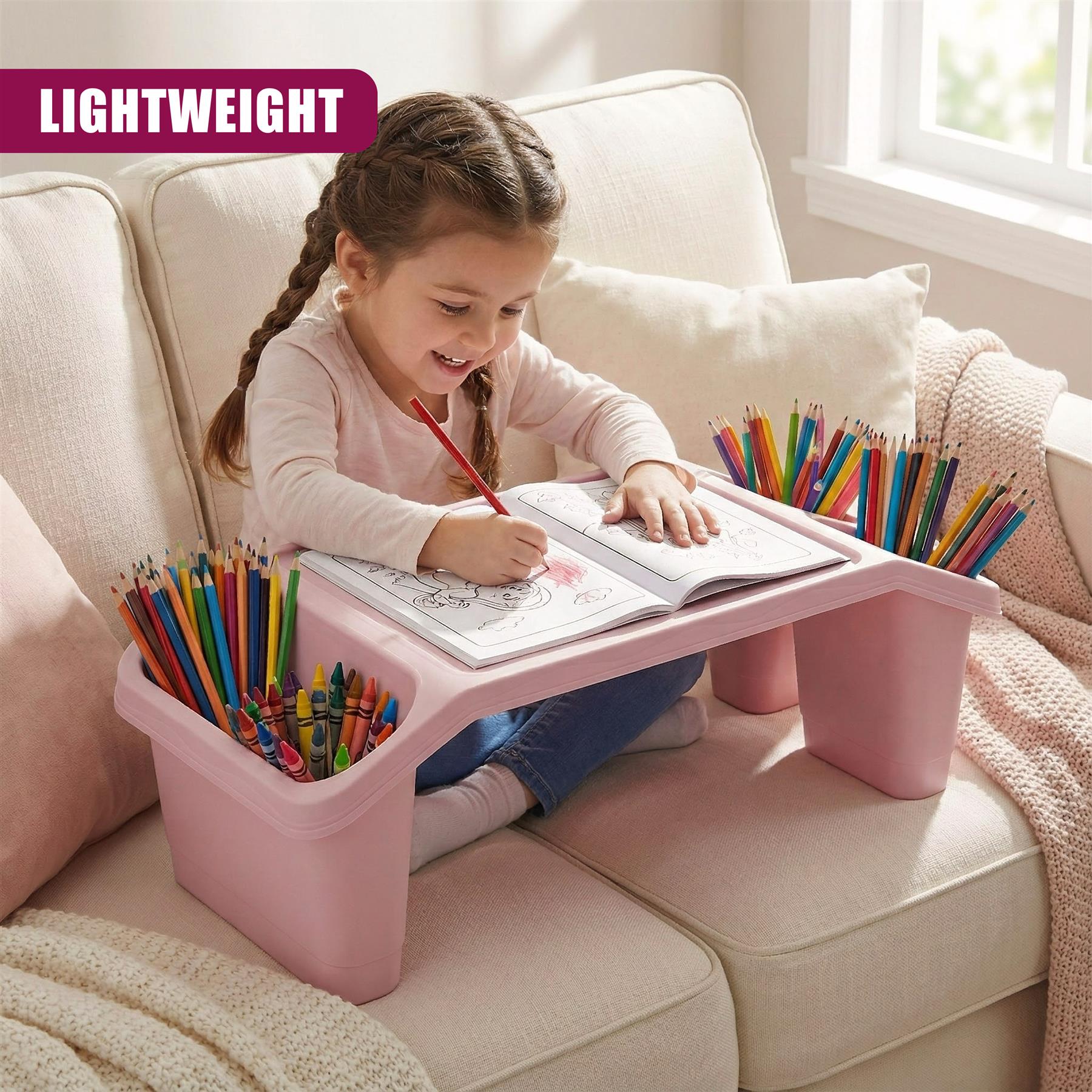 A young girl sits on a couch, surrounded by a pink desk and a tray of colored pencils. She is drawing on a large piece of paper, with a pencil in her hand. The desk is designed to be a comfortable and stable place for a child to work on their drawing or other activities. - The Magic Toy Shop